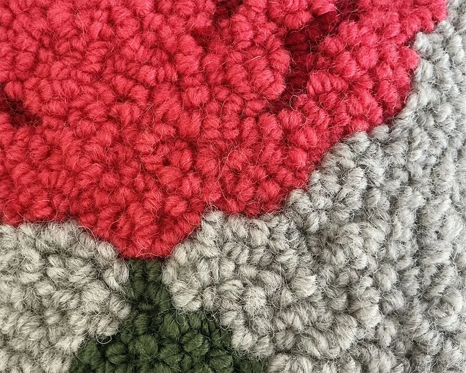 Detail of hand-hooked wool forming the stylized alpine flower motif.