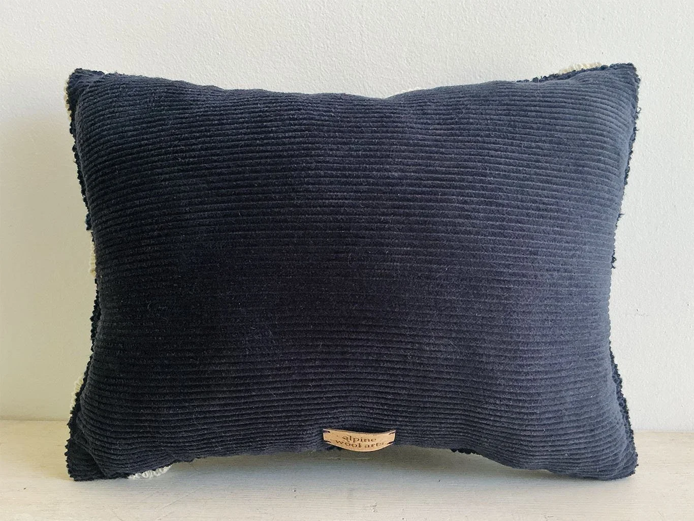 Back of pillow in deep blue cotton corduroy fabric.