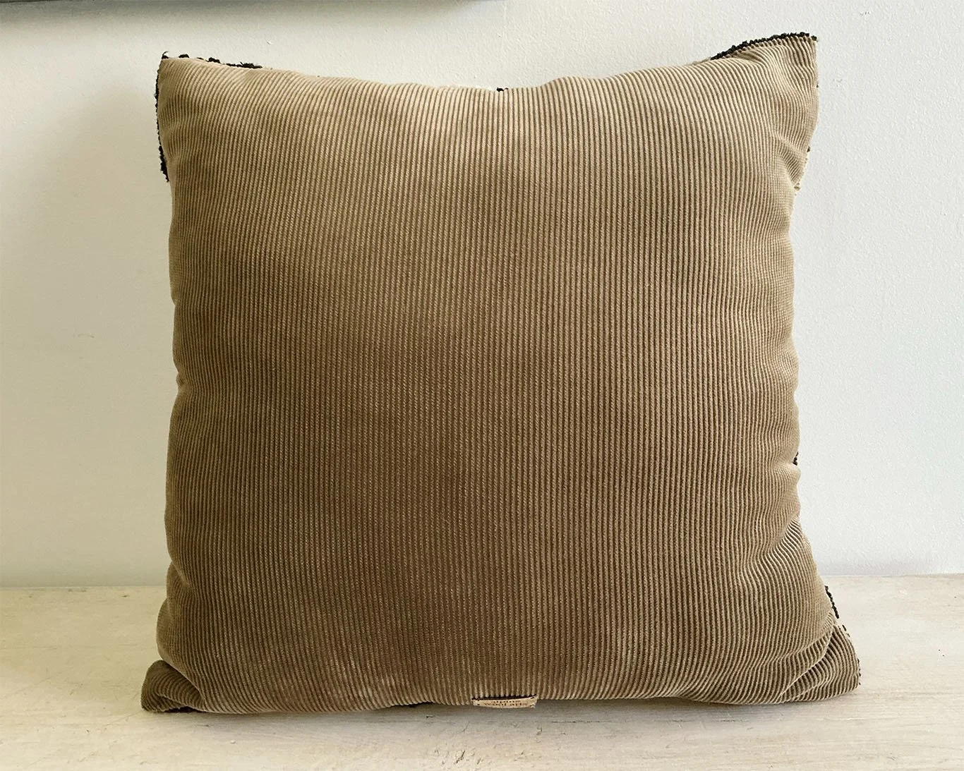 Back of pillow in camel cotton corduroy fabric.