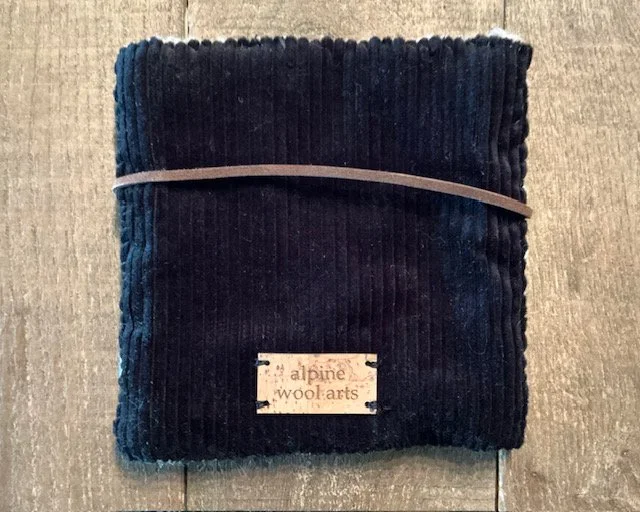 Back of hand-hooked wool panel in black, showing dense texture and fiber variation.