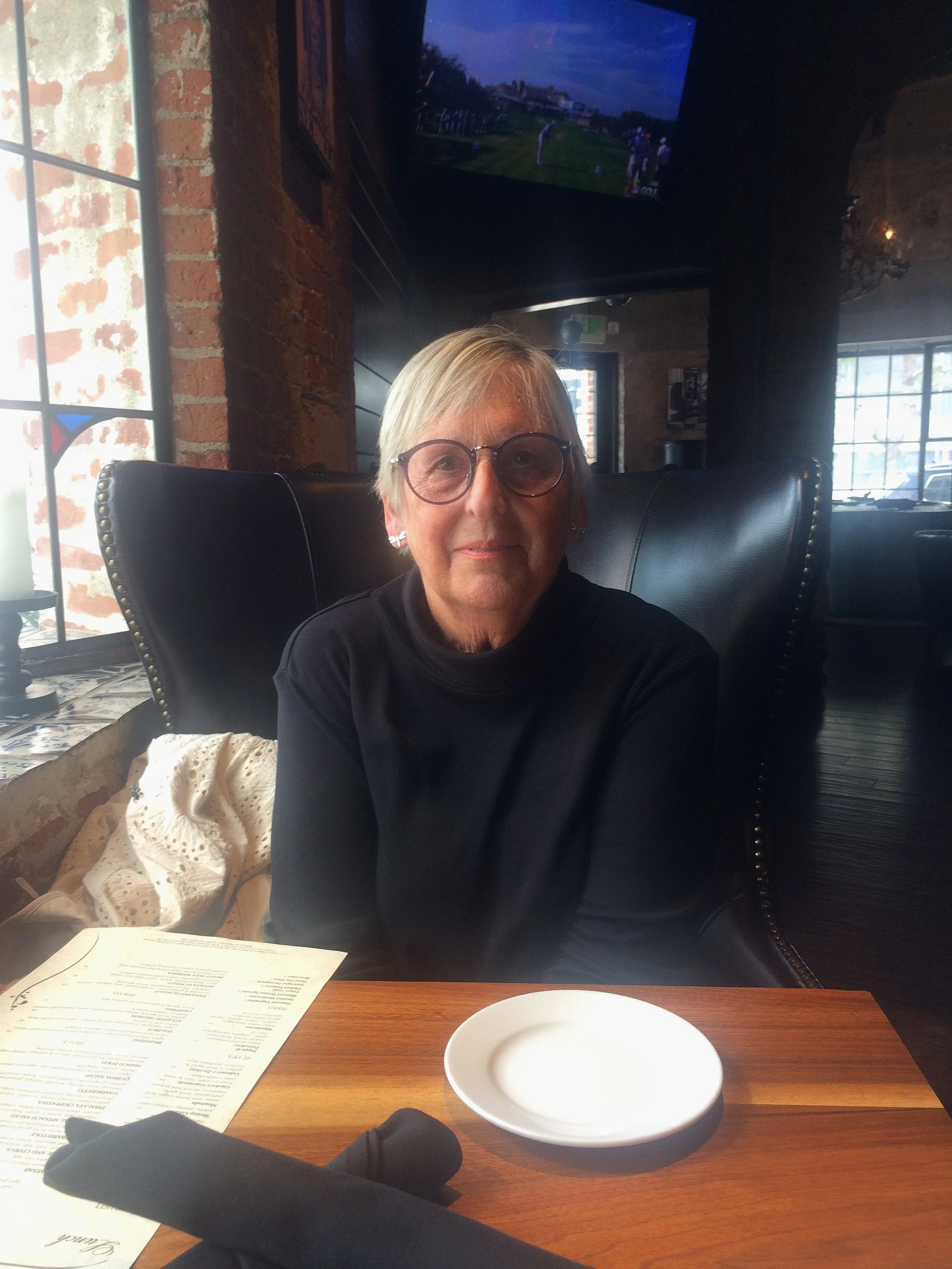 A woman with short blonde hair and glasses.