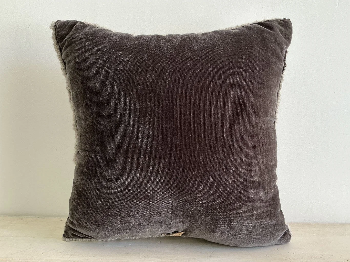 Back of pillow in dark brown cotton velvet fabric.