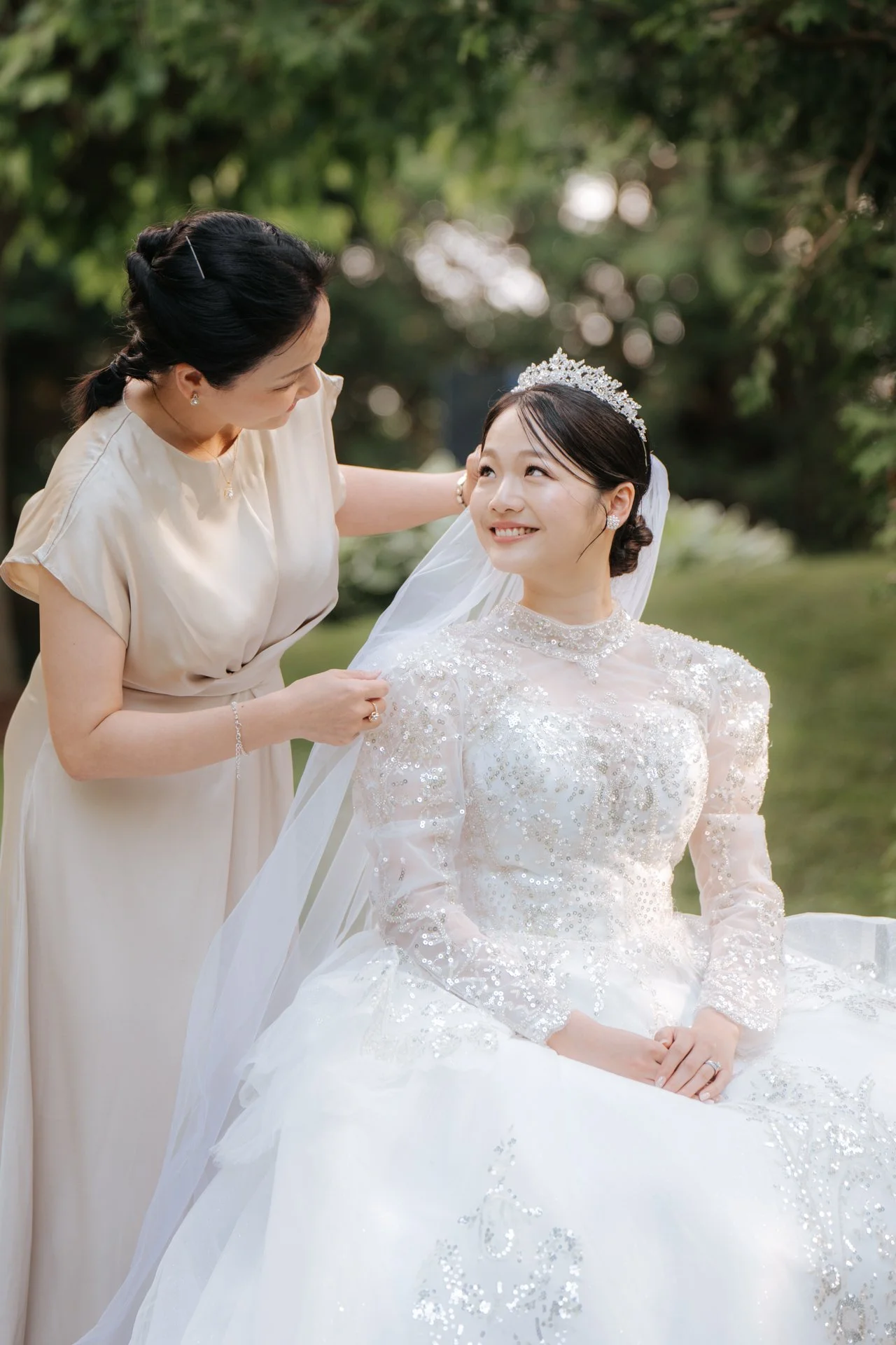  Mother of the bride adjusting the veil on her daughter, an emotional wedding preparation moment. 