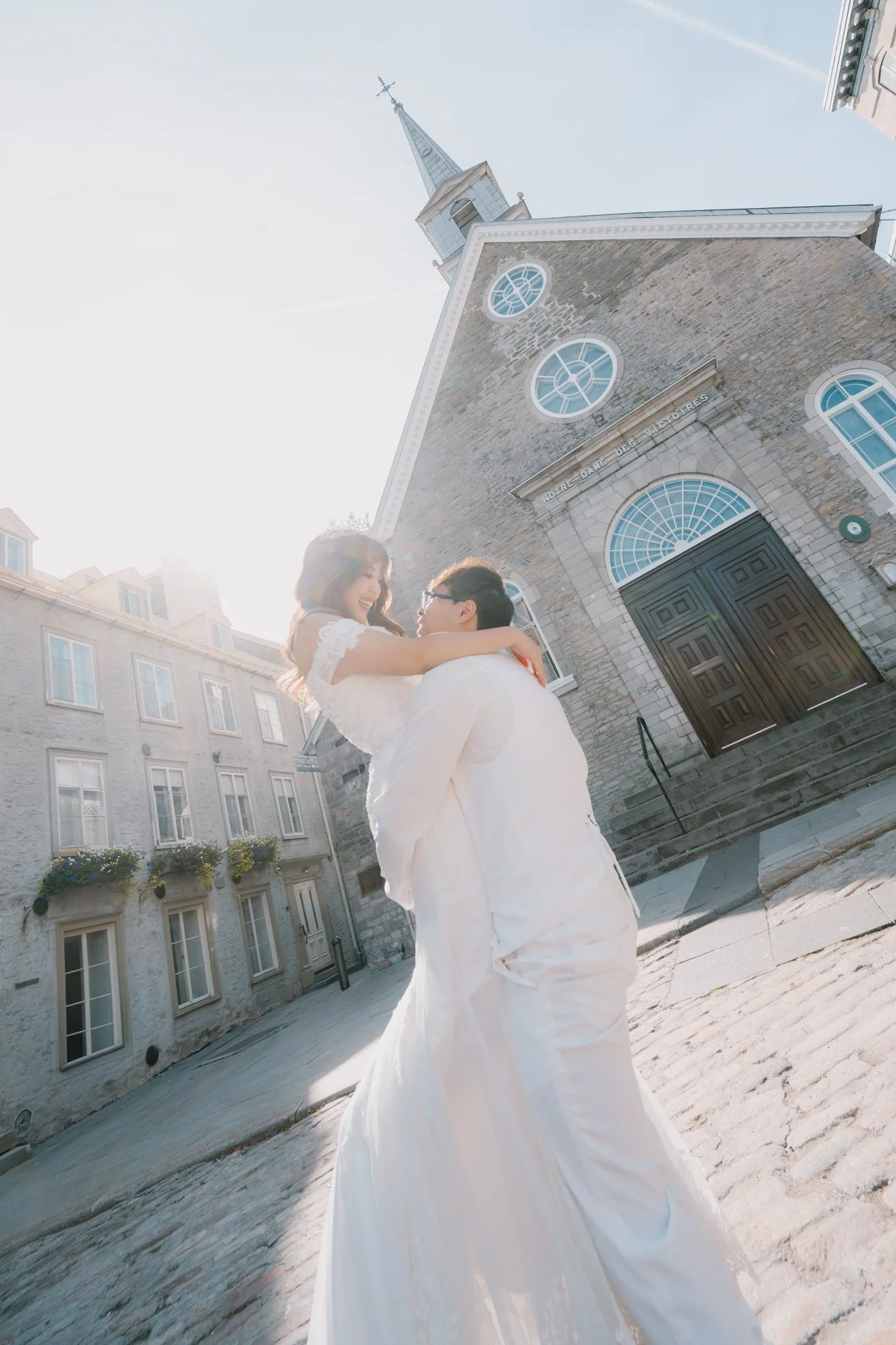  Groom lifting the bride in front of the stone church  