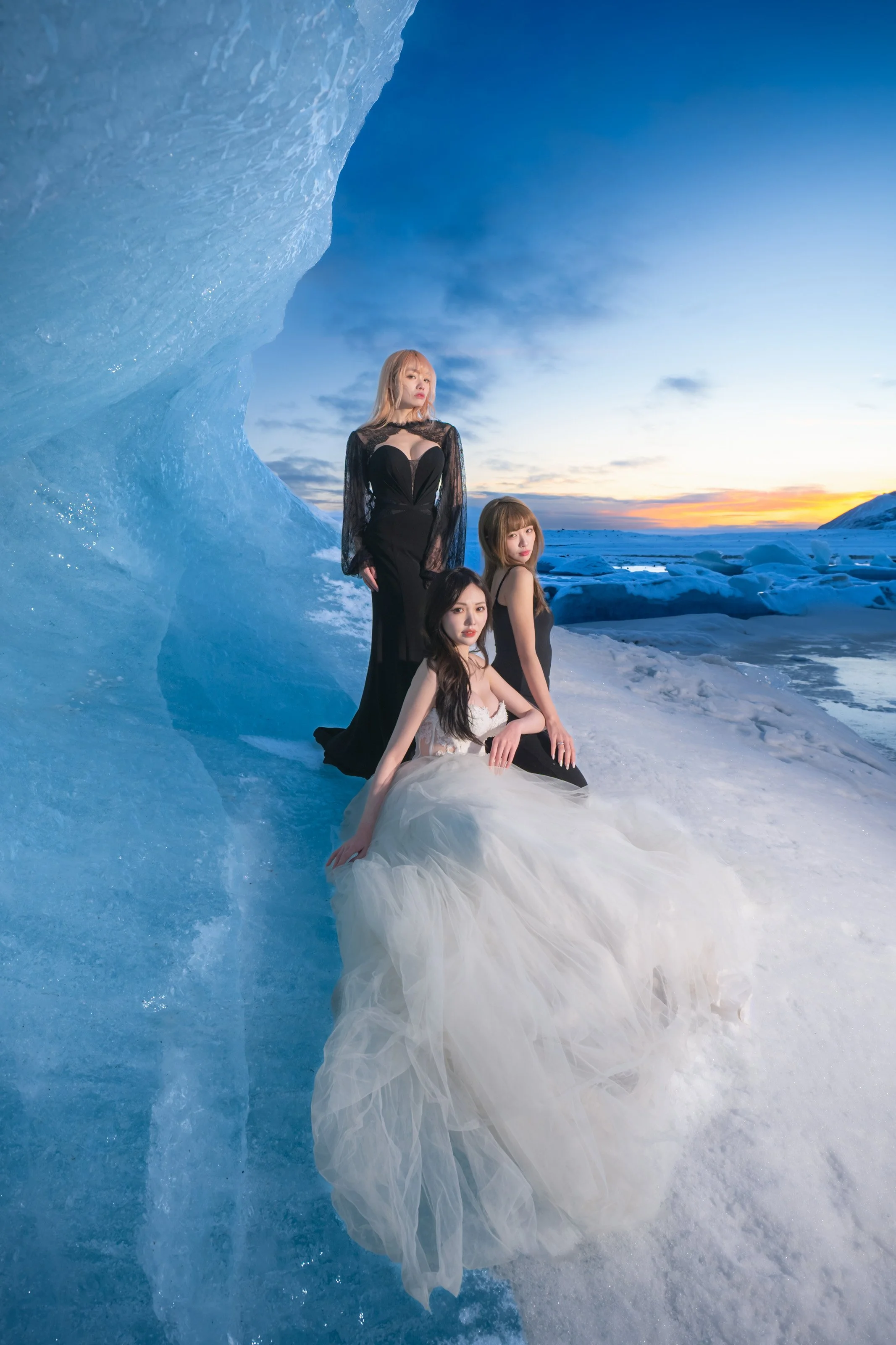 Three women posing by the vibrant blue ice wall