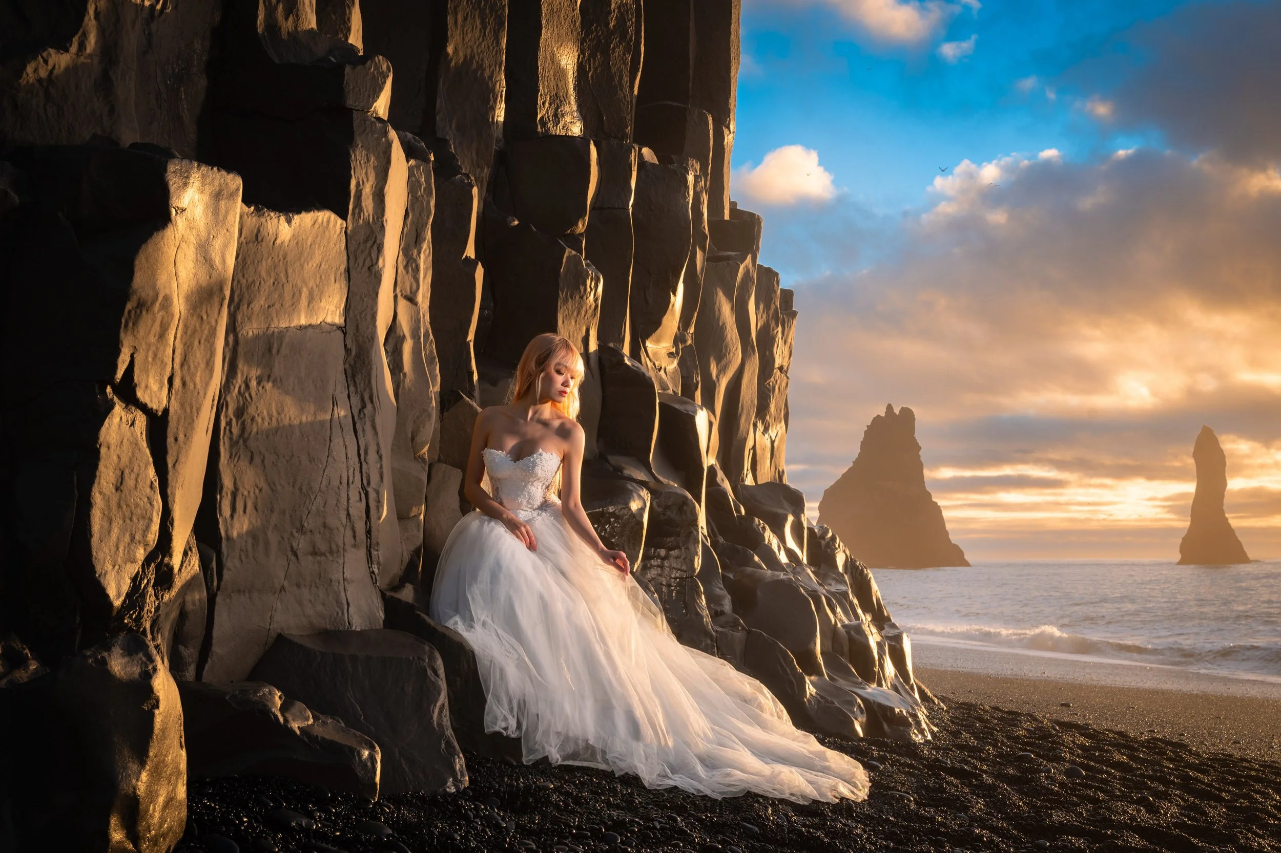 Bride sitting on the basalt columns bathed in golden light