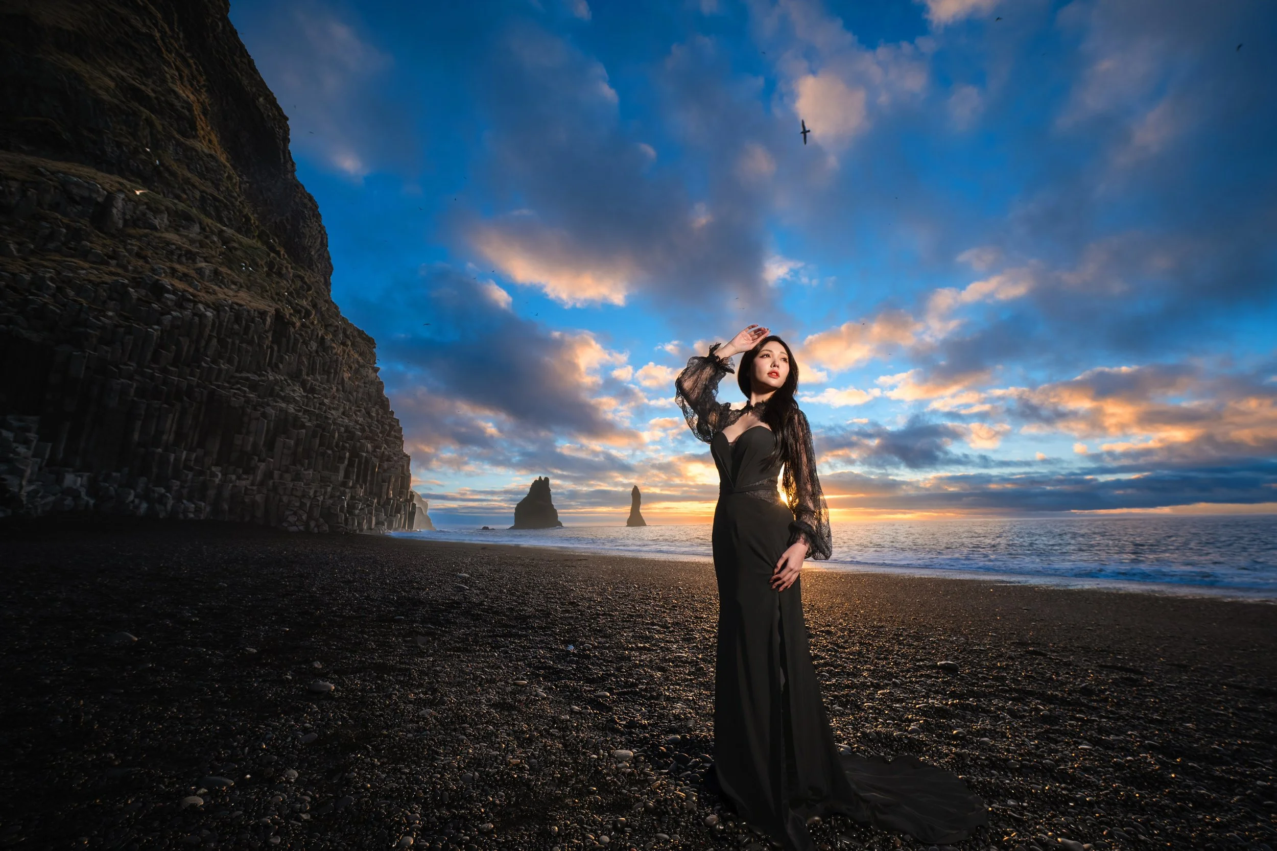 Woman in black gown posing against the basalt columns