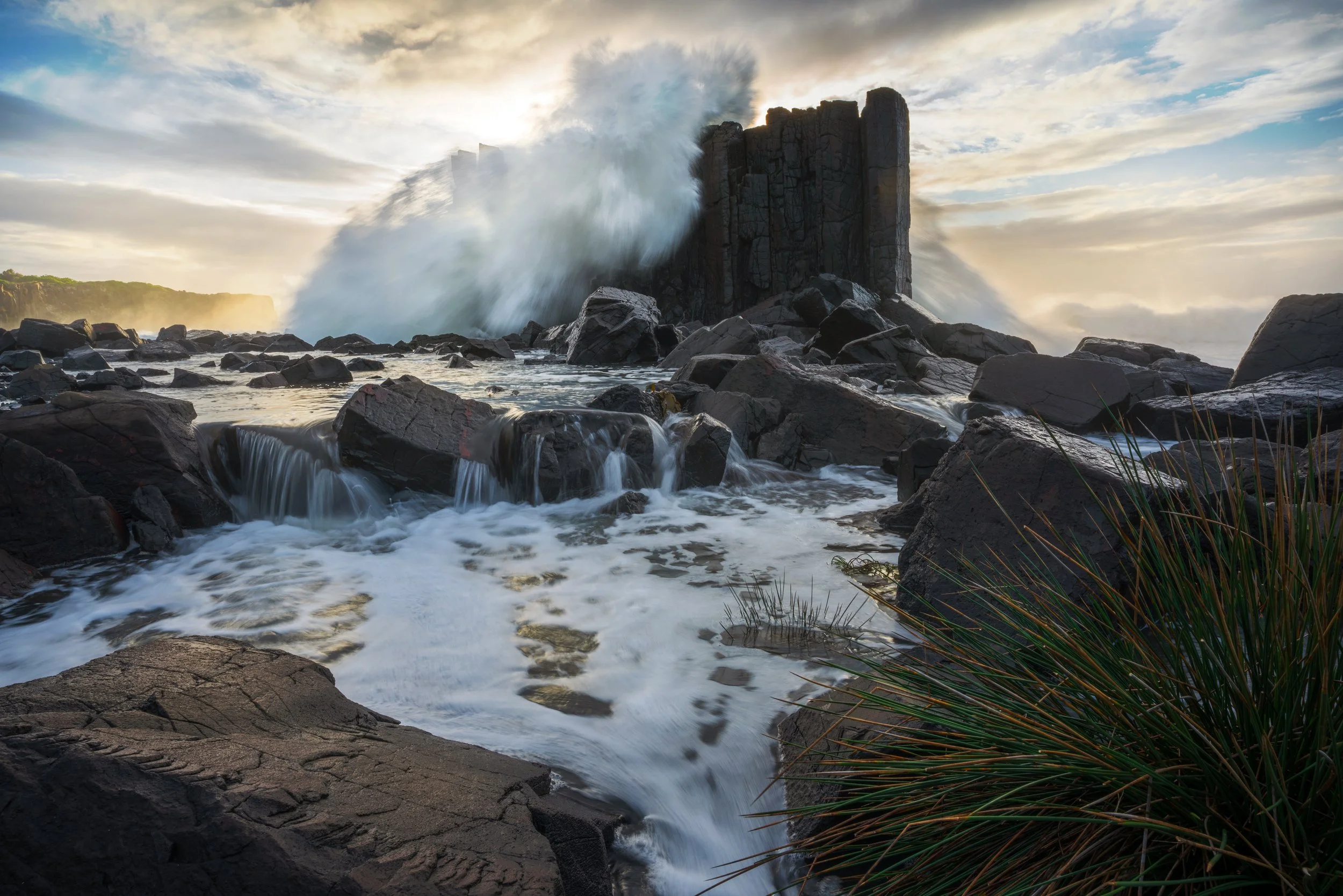 A monster wave crashes over the largest rock formation at Bombo Quarry