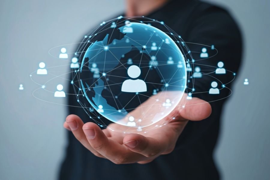 A person in a suit holds out their hand, with a digital globe surrounded by interconnected human icons above it, symbolizing global connectivity and social networks.