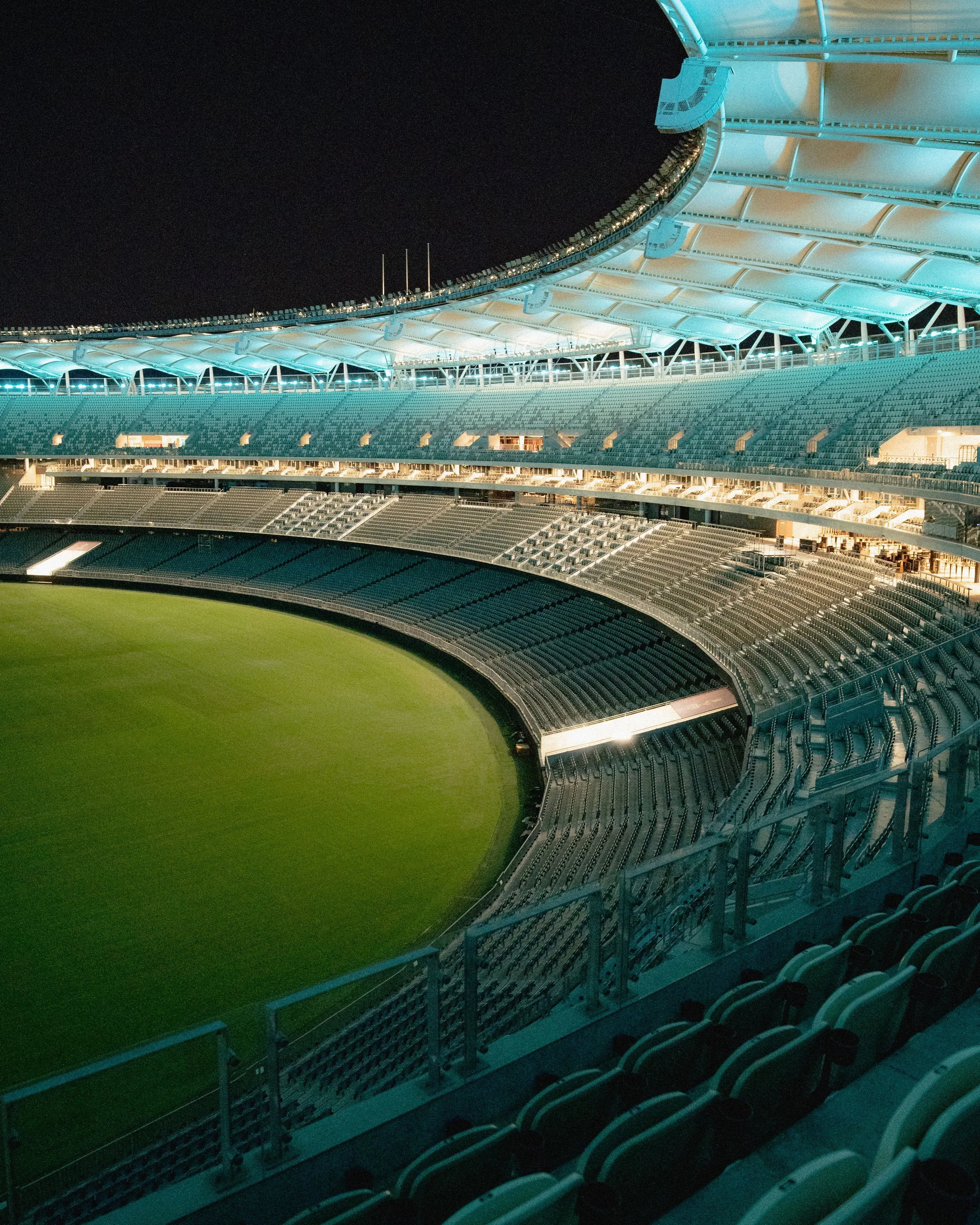 Empty footballstadium at night with illuminated seating and field