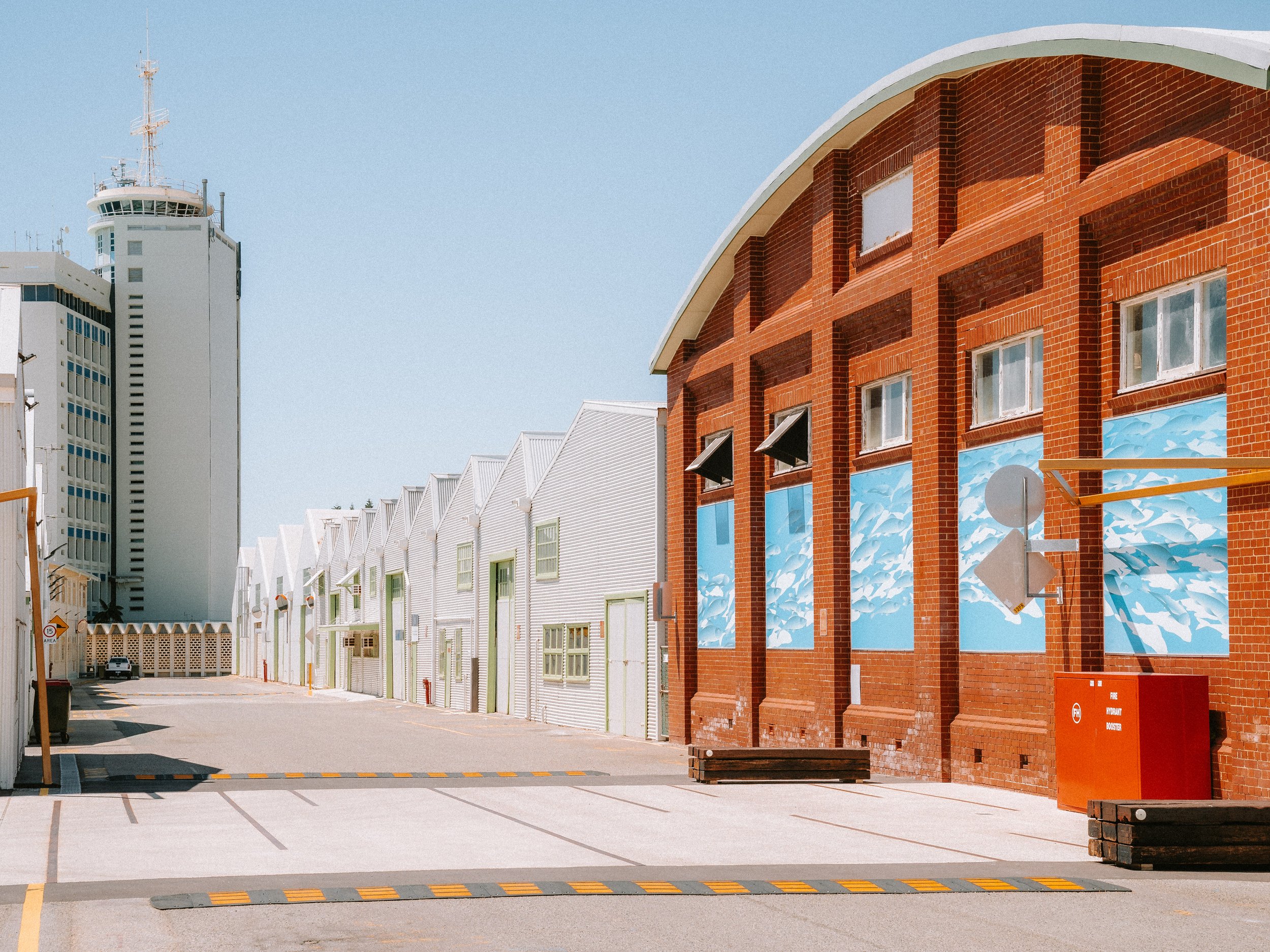 Empty parking lot next to white and brick buildings under a clear blue sky.