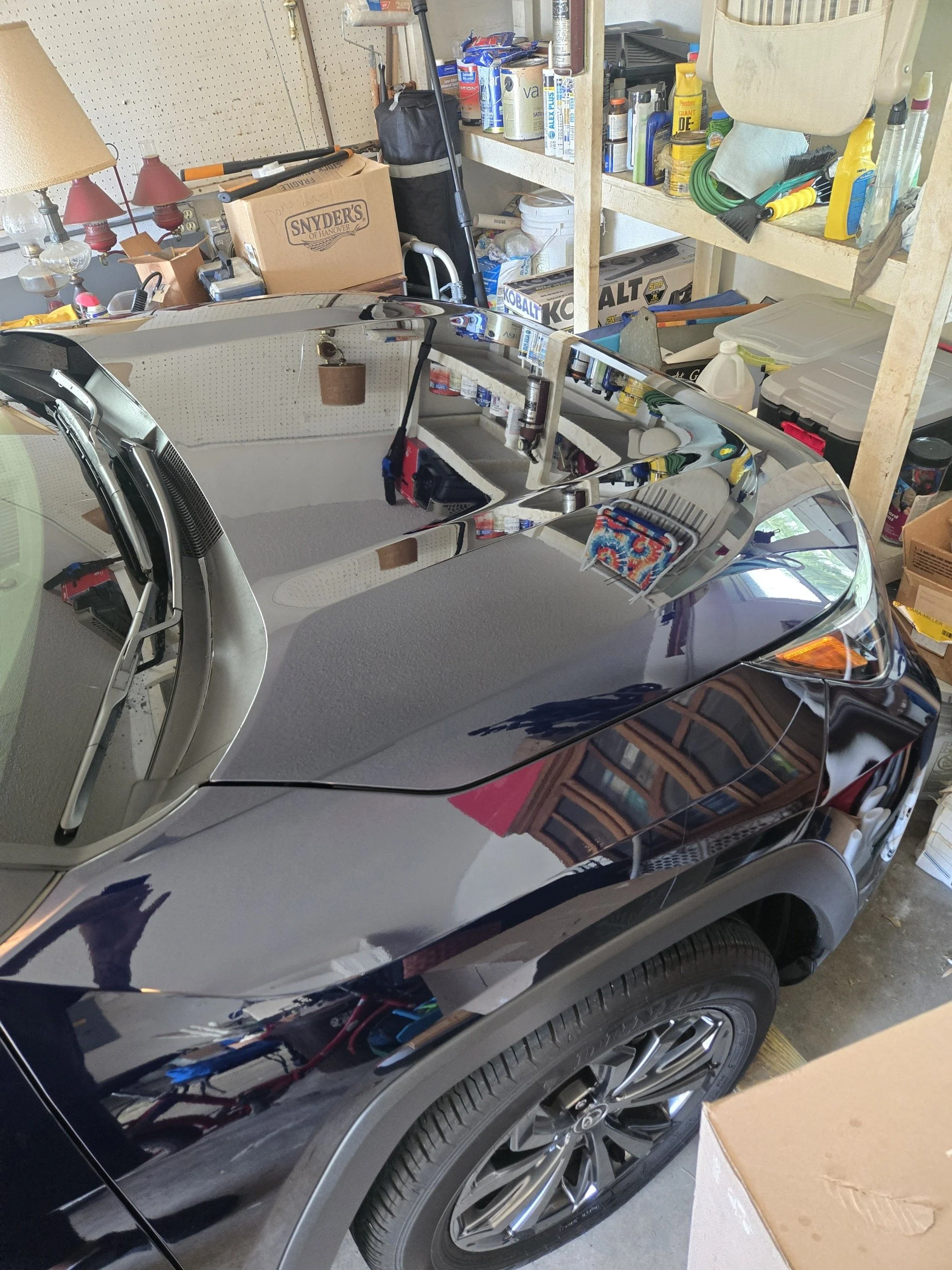  The car's surface is highly reflective, mirroring parts because of a ceramic coating application by wash boss.