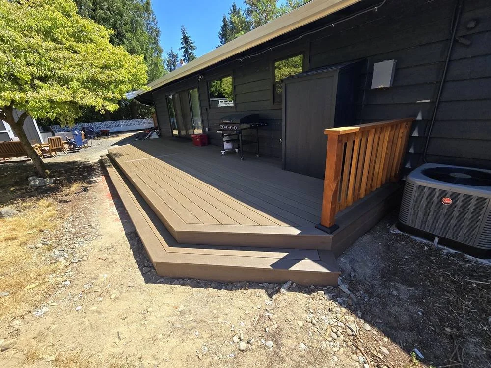 Low-level composite back deck with cedar railing beside the water heater enclosure