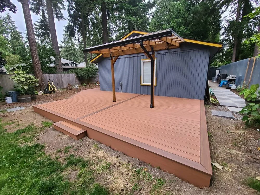 PVC deck with picture-frame border, step and patio cover beside a blue house