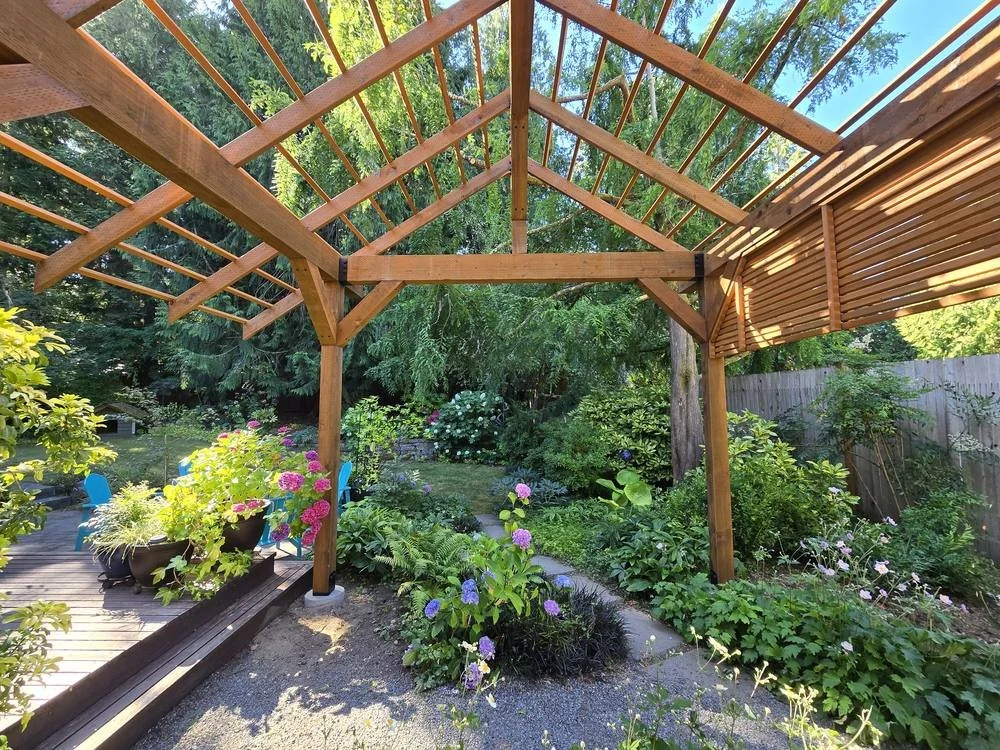 View from under the timber frame pergola toward the backyard garden and deck