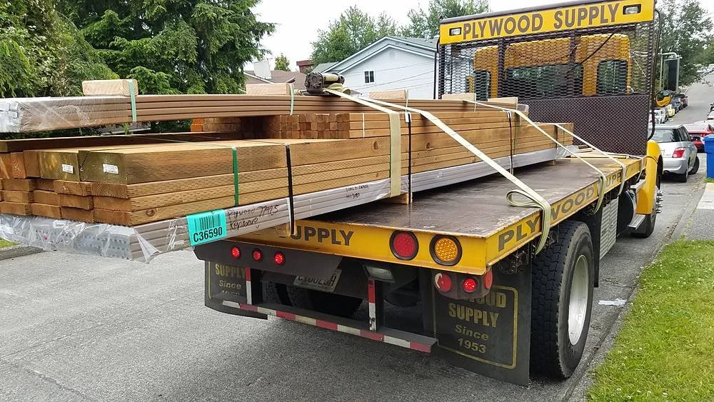 Lumber delivery truck dropping off deck materials at a job site