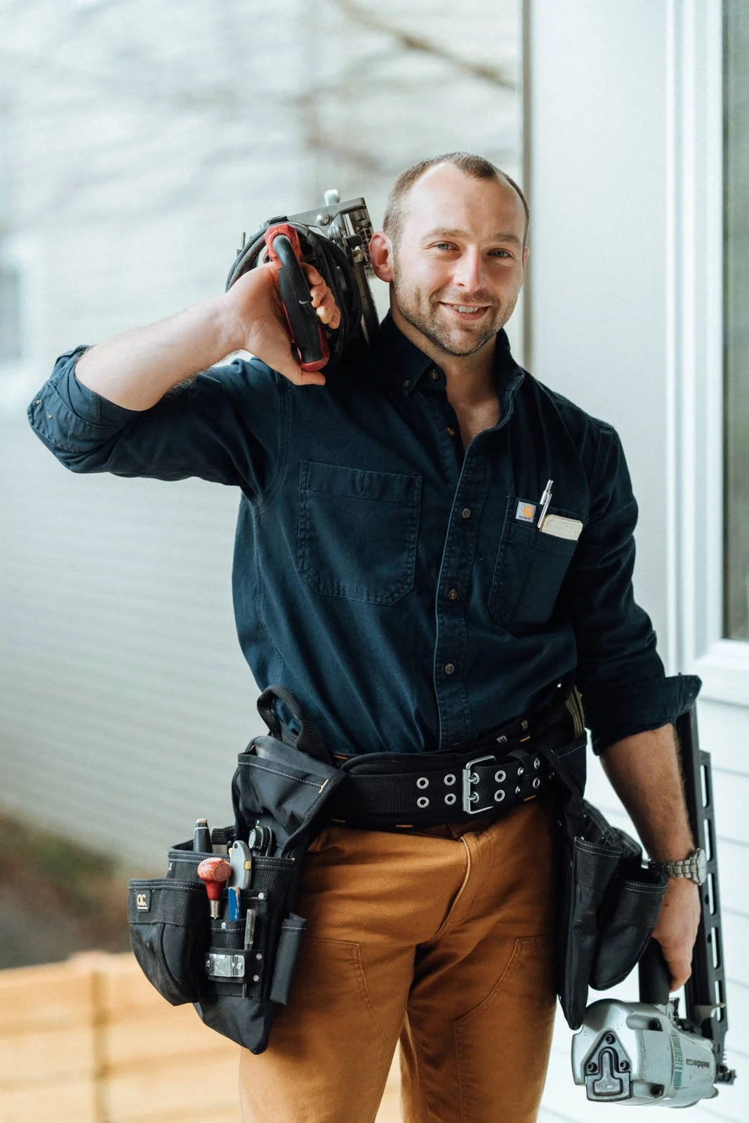 Owner of Tool & Trade Construction holding framing tools and wearing a tool belt.