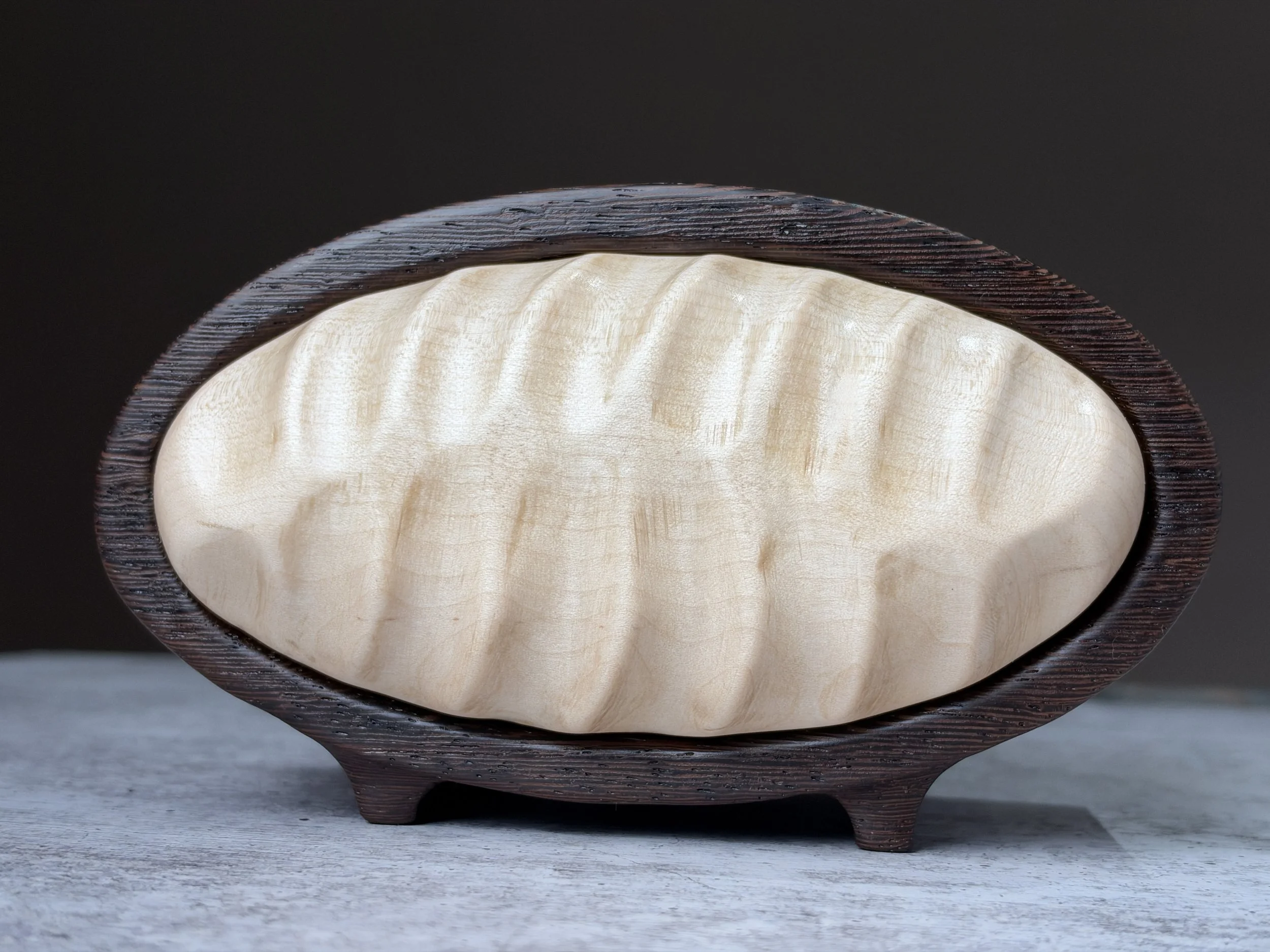 Hand-carved curly maple drawer front framed by dark wenge.