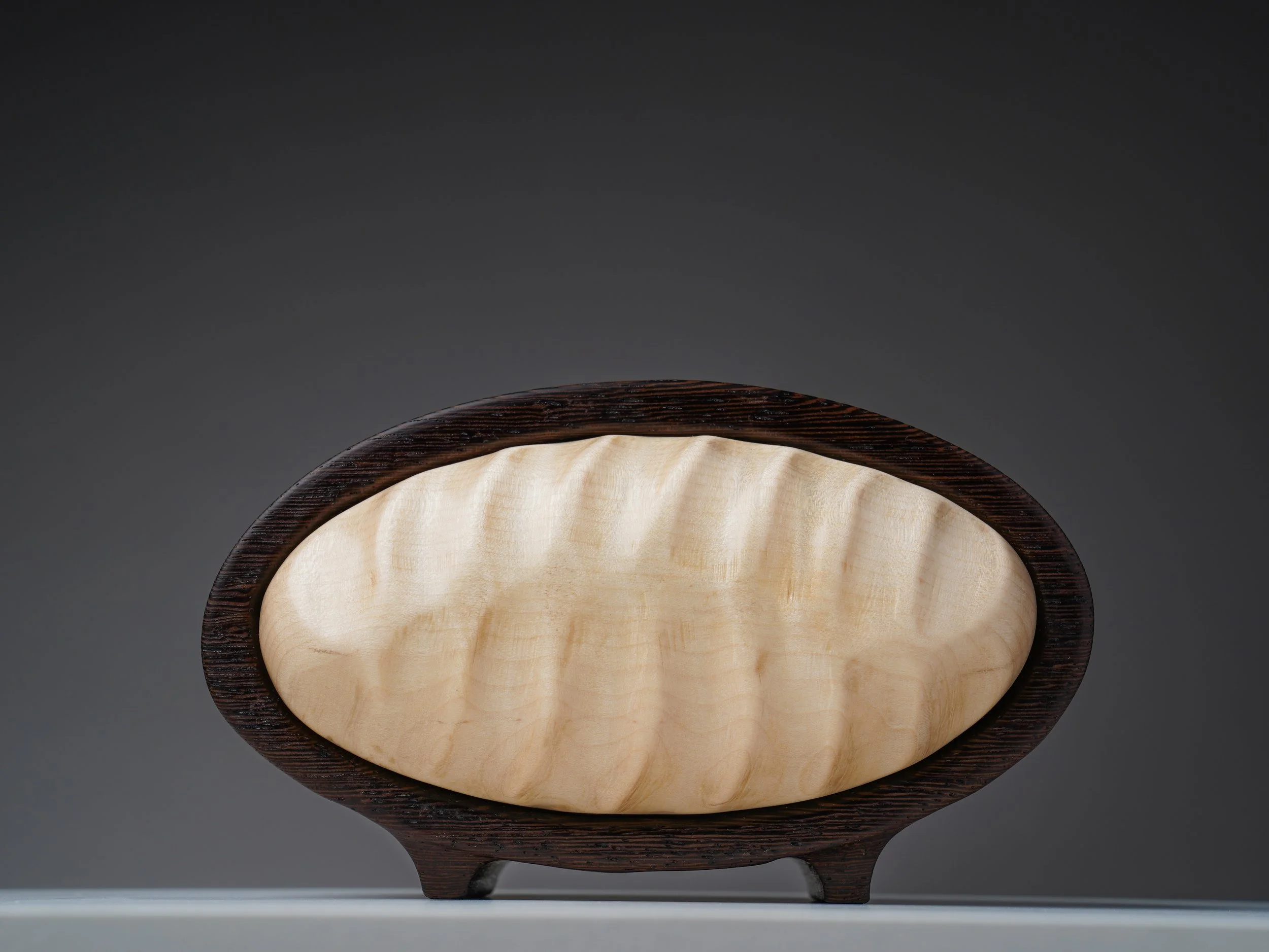 Wenge keepsake box with textured curly maple front and small feet.