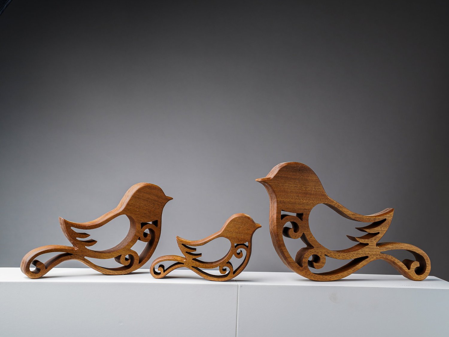 Three African walnut wooden birds with decorative cutout details