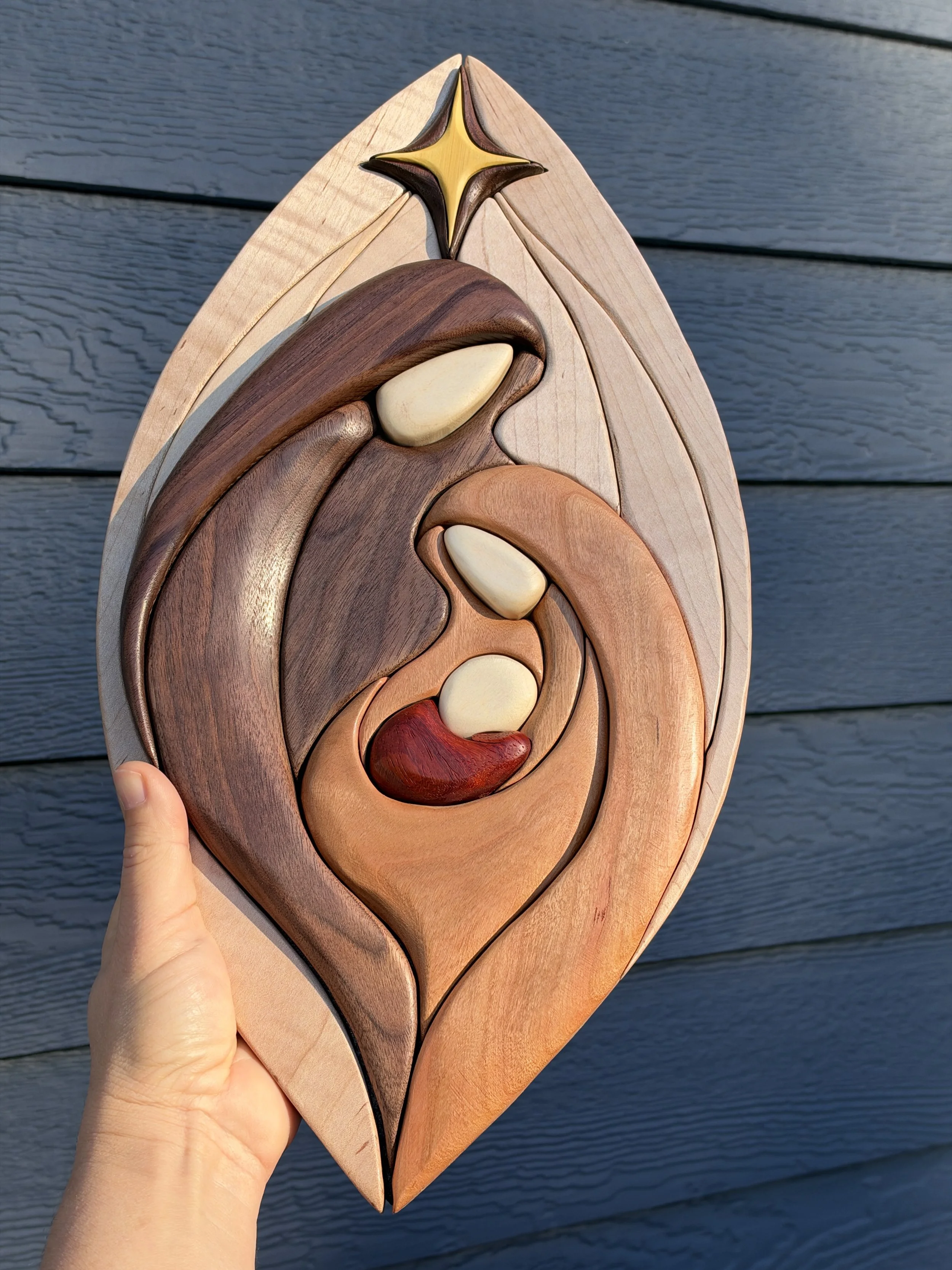 Natural wood nativity wall art against dark siding