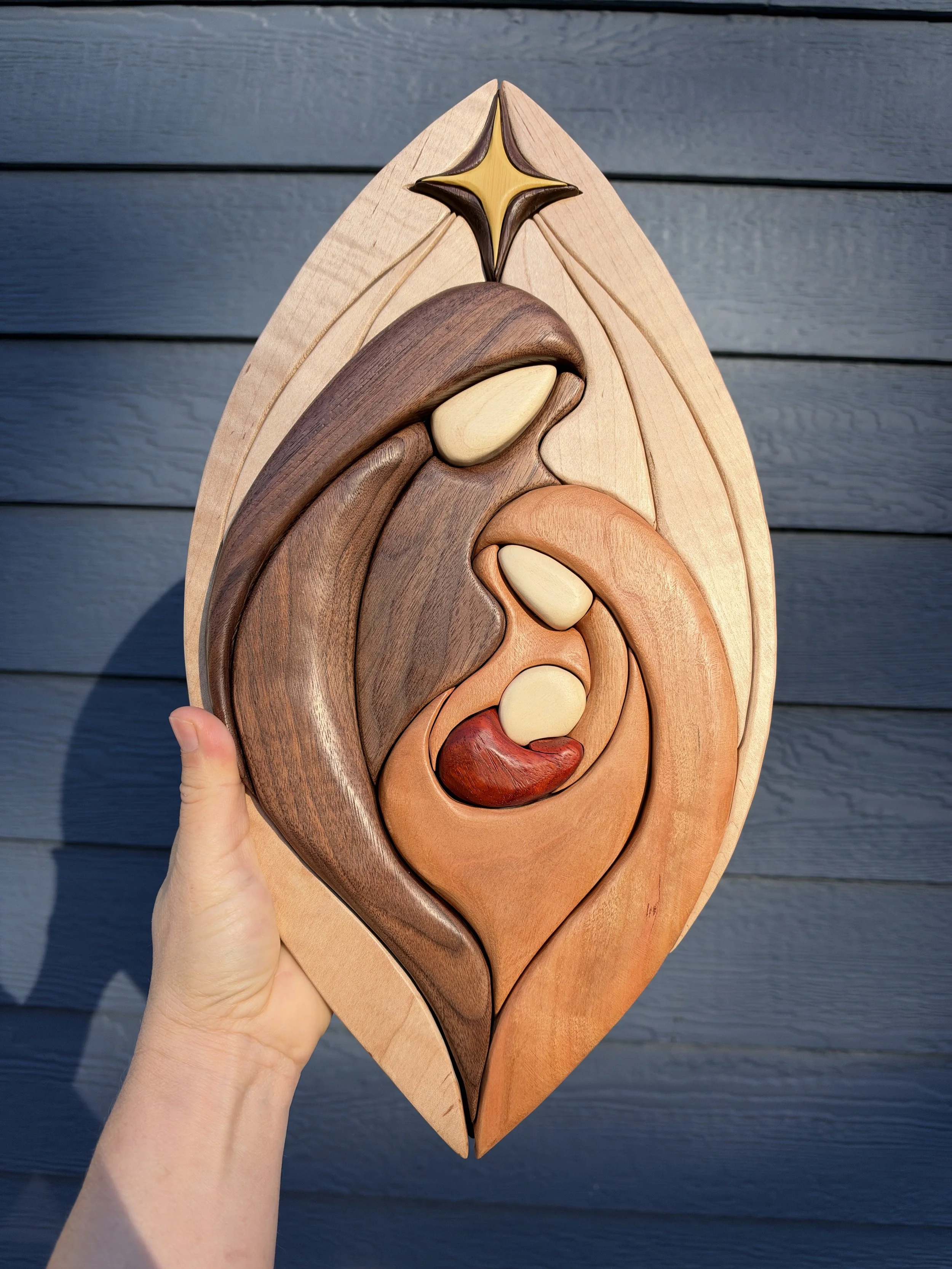 Front view of the nativity wall art held against dark siding