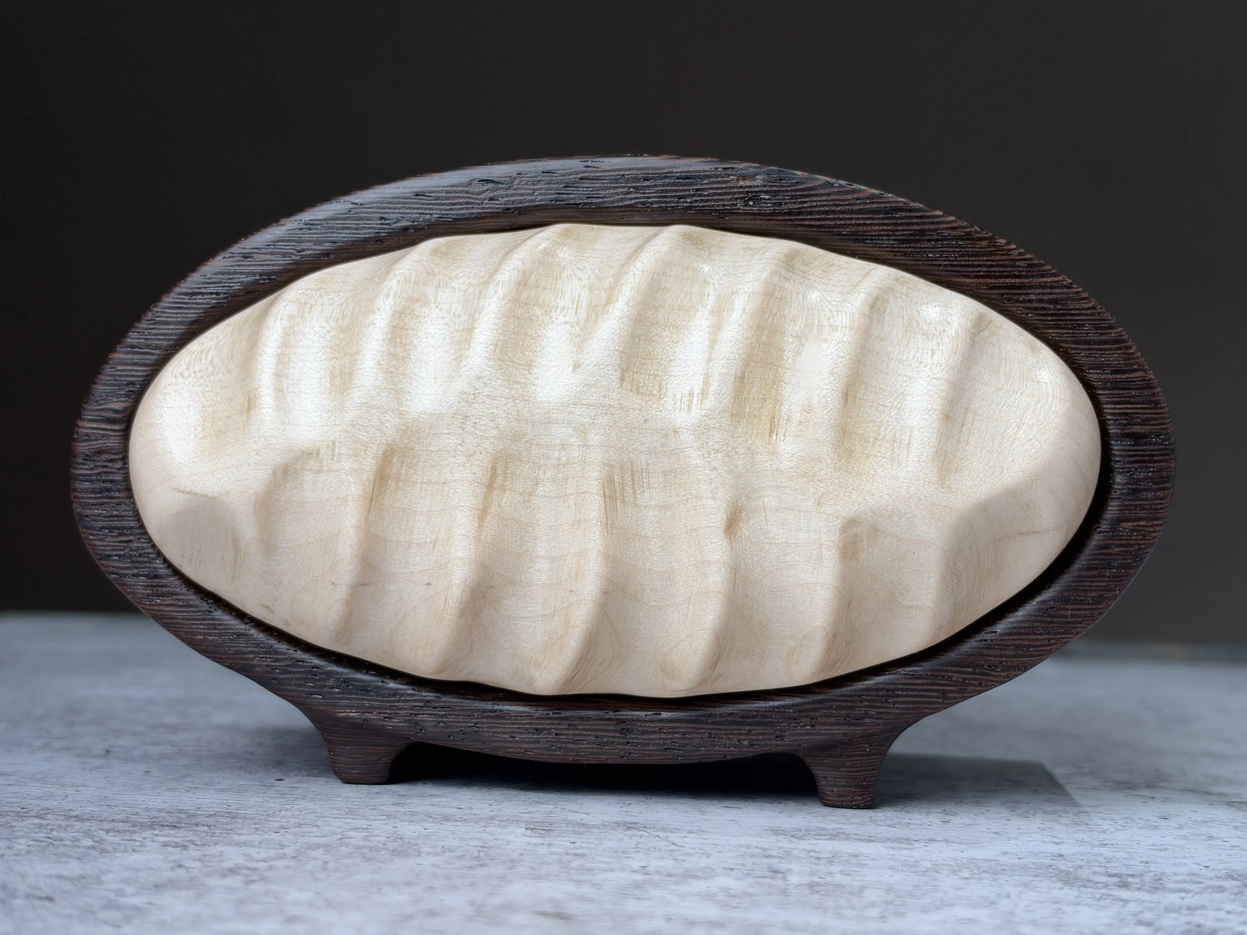 Close view of flowing waves carved into the curly maple drawer front.
