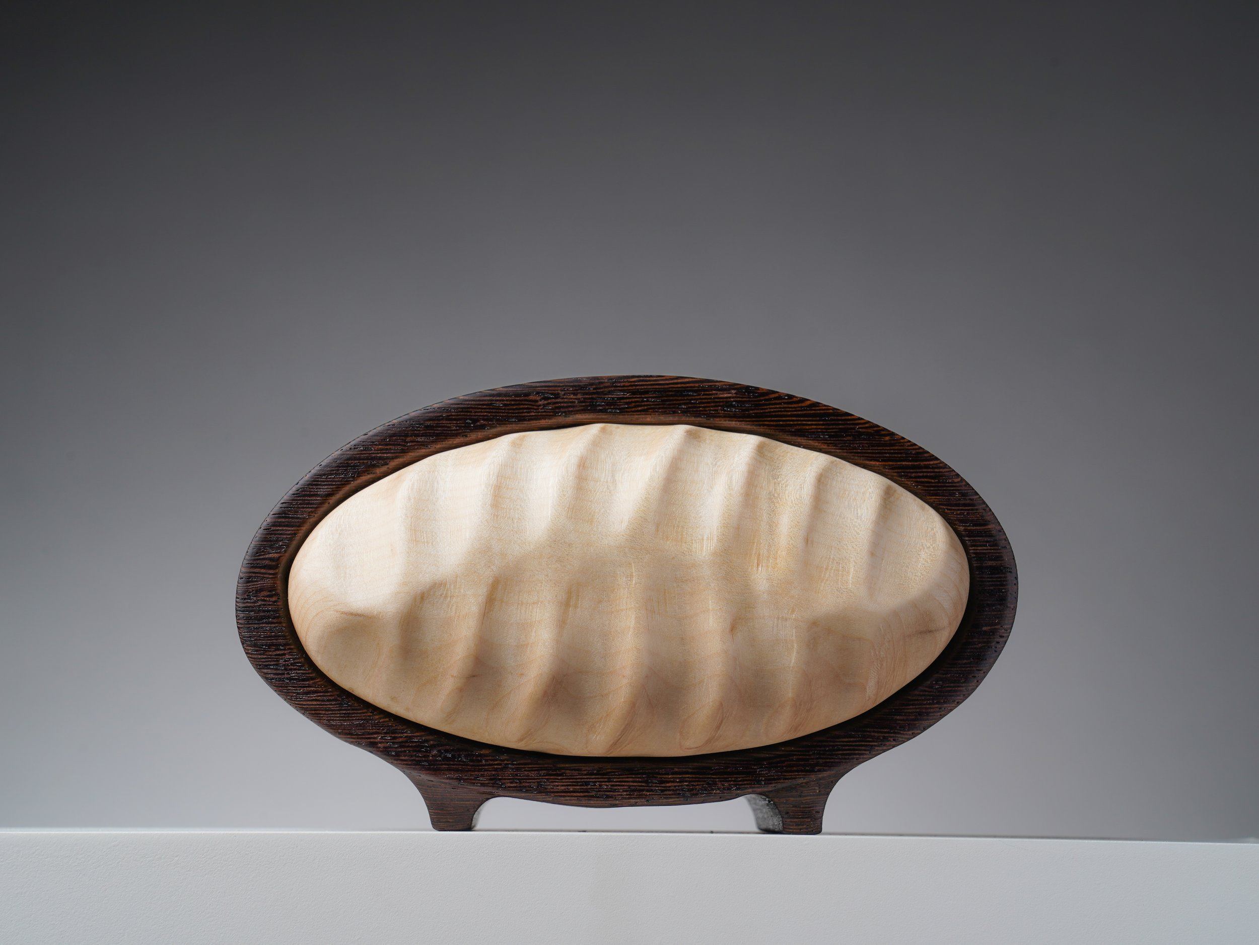 Handcrafted oval bandsaw box with contrasting dark wenge and pale carved maple.