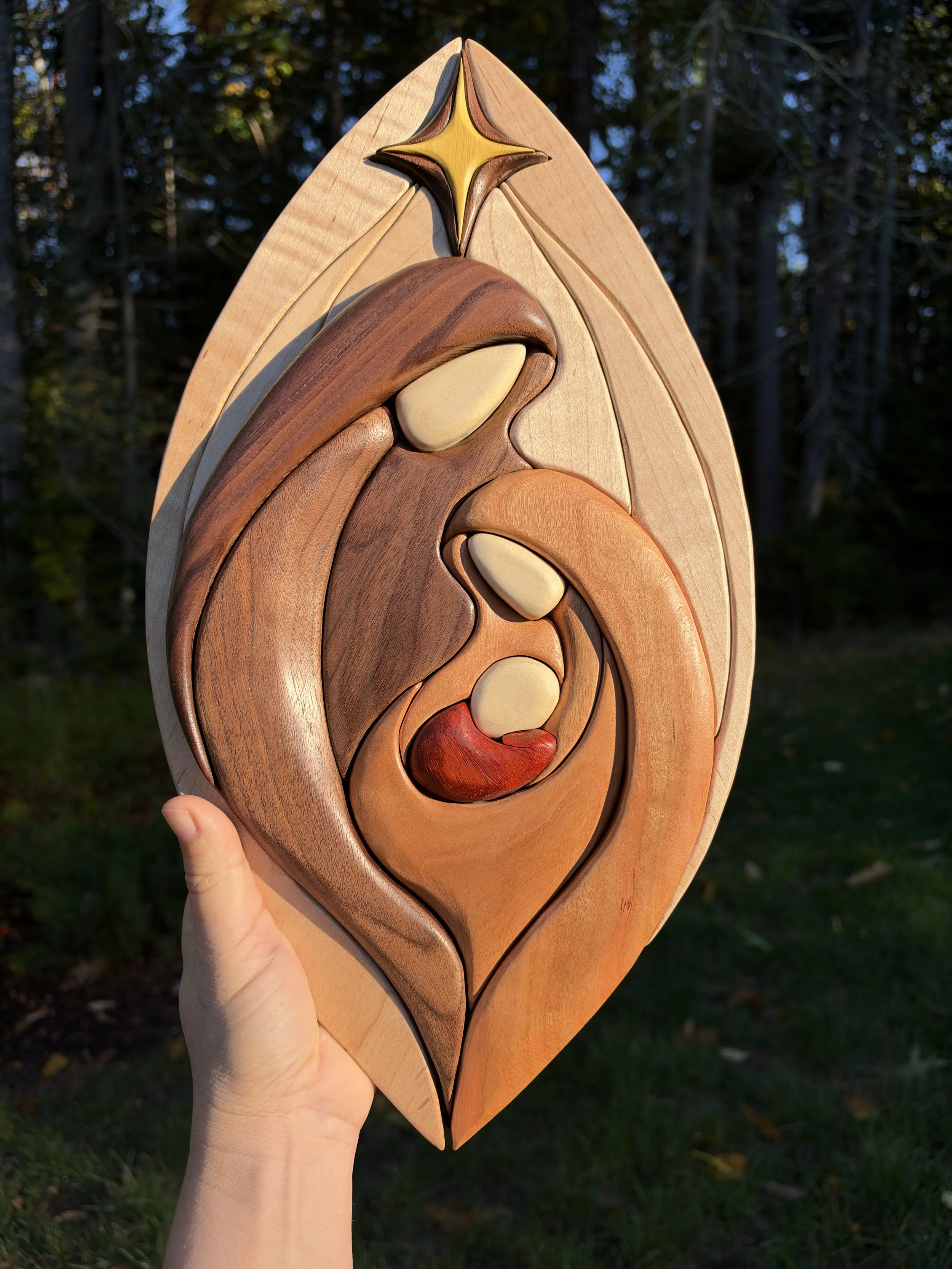 Handmade wooden intarsia nativity wall art depicting Mary, Joseph and baby Jesus beneath a star