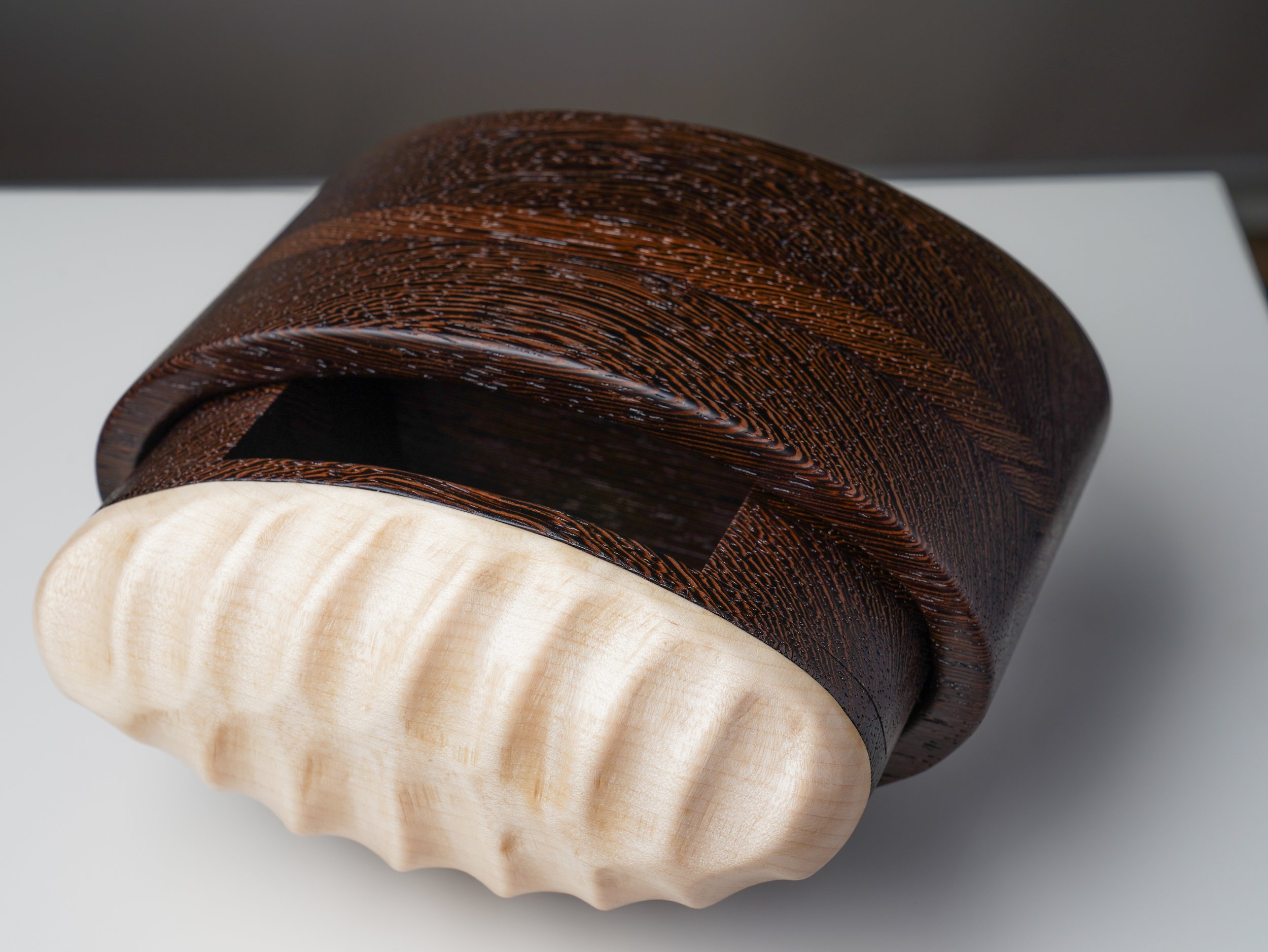 Close view of the carved maple drawer front and dark wenge body.
