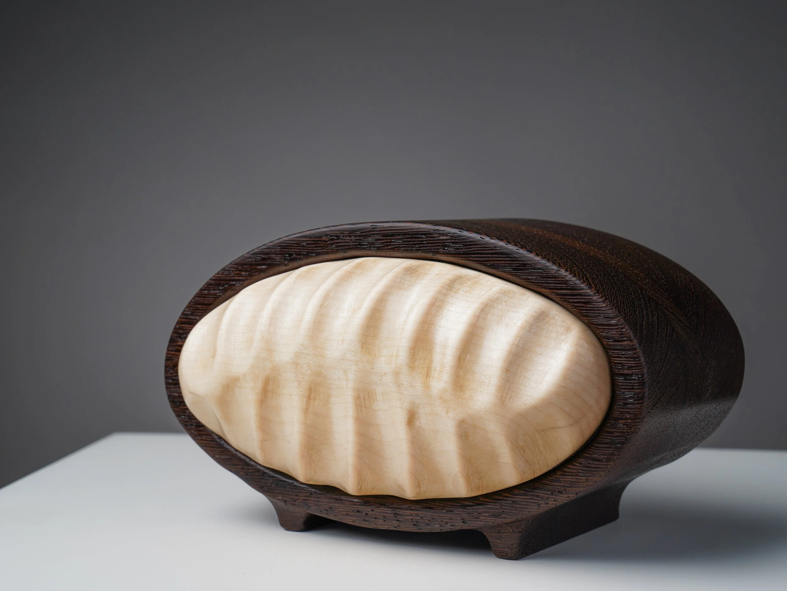 Angled view of the oval wenge and curly maple keepsake box.