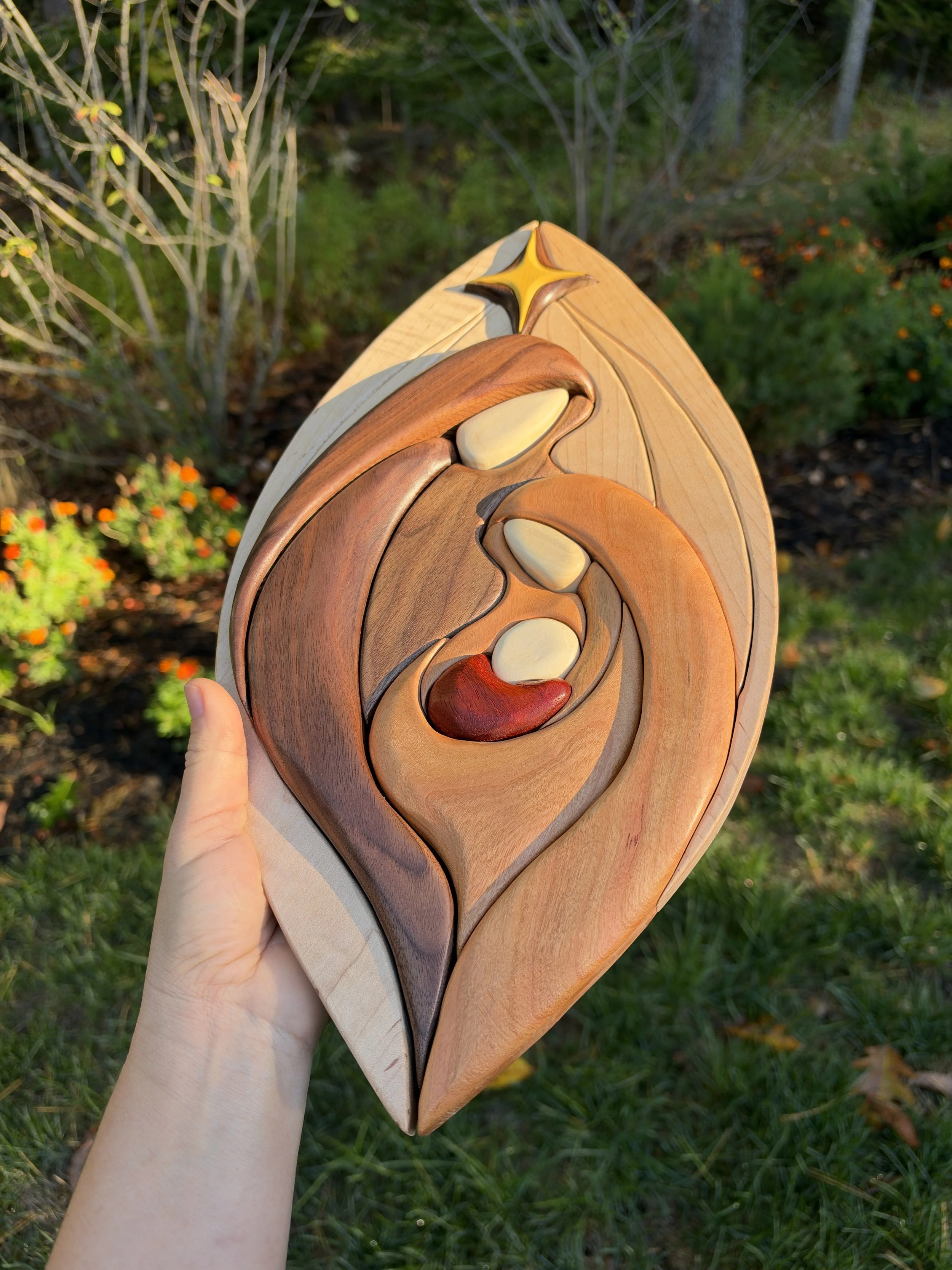 Wooden nativity wall art with a star above Mary, Joseph and baby Jesus