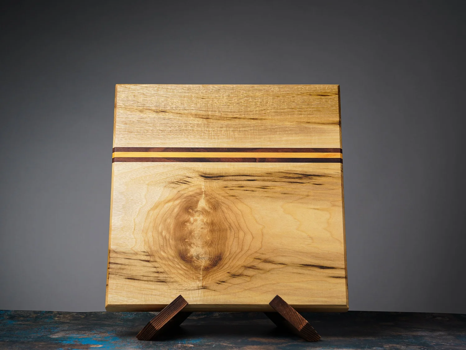 Square myrtlewood cutting board with natural grain and narrow accent stripes