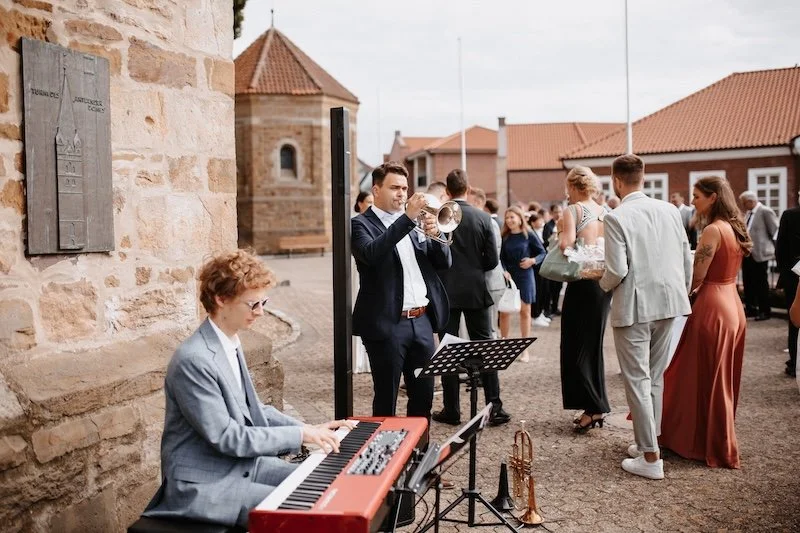 Musiker spielen draußen bei einem Hochzeitsempfang. 