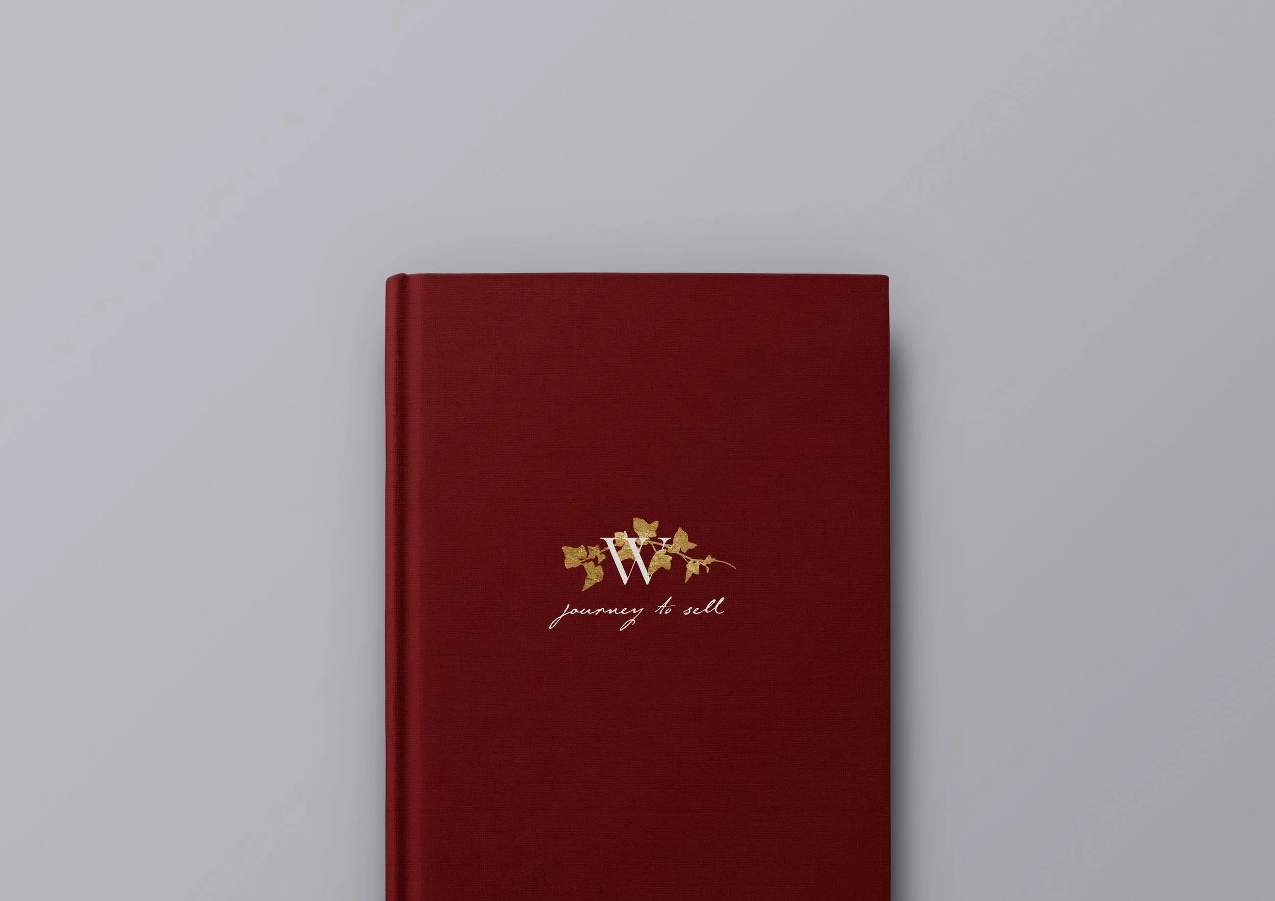 Red journal with a gold floral design and the words "journey to self" on a gray background.