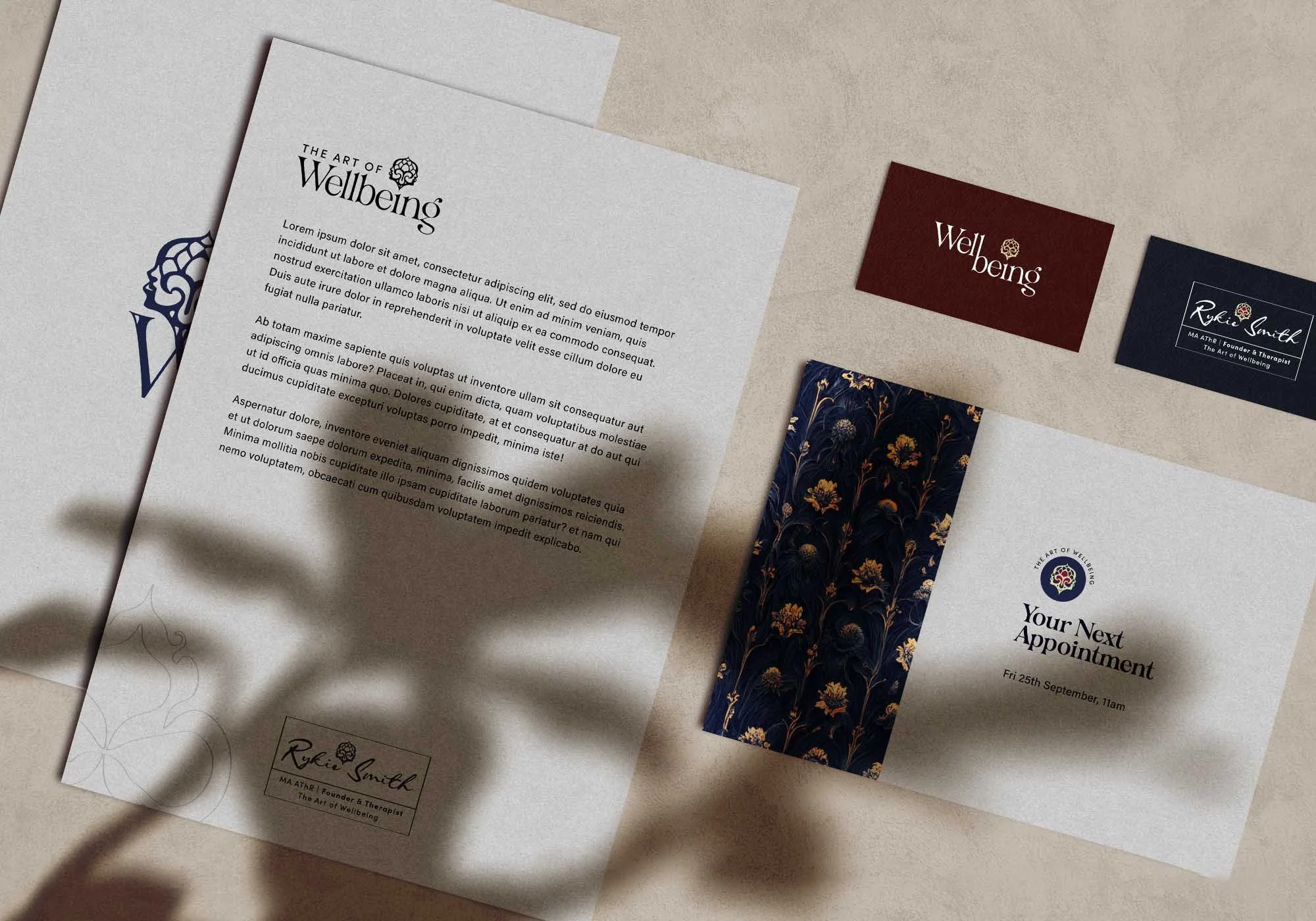 Various business cards and flyers for wellbeing and therapy services, with elegant designs and text, laid out on a beige surface.