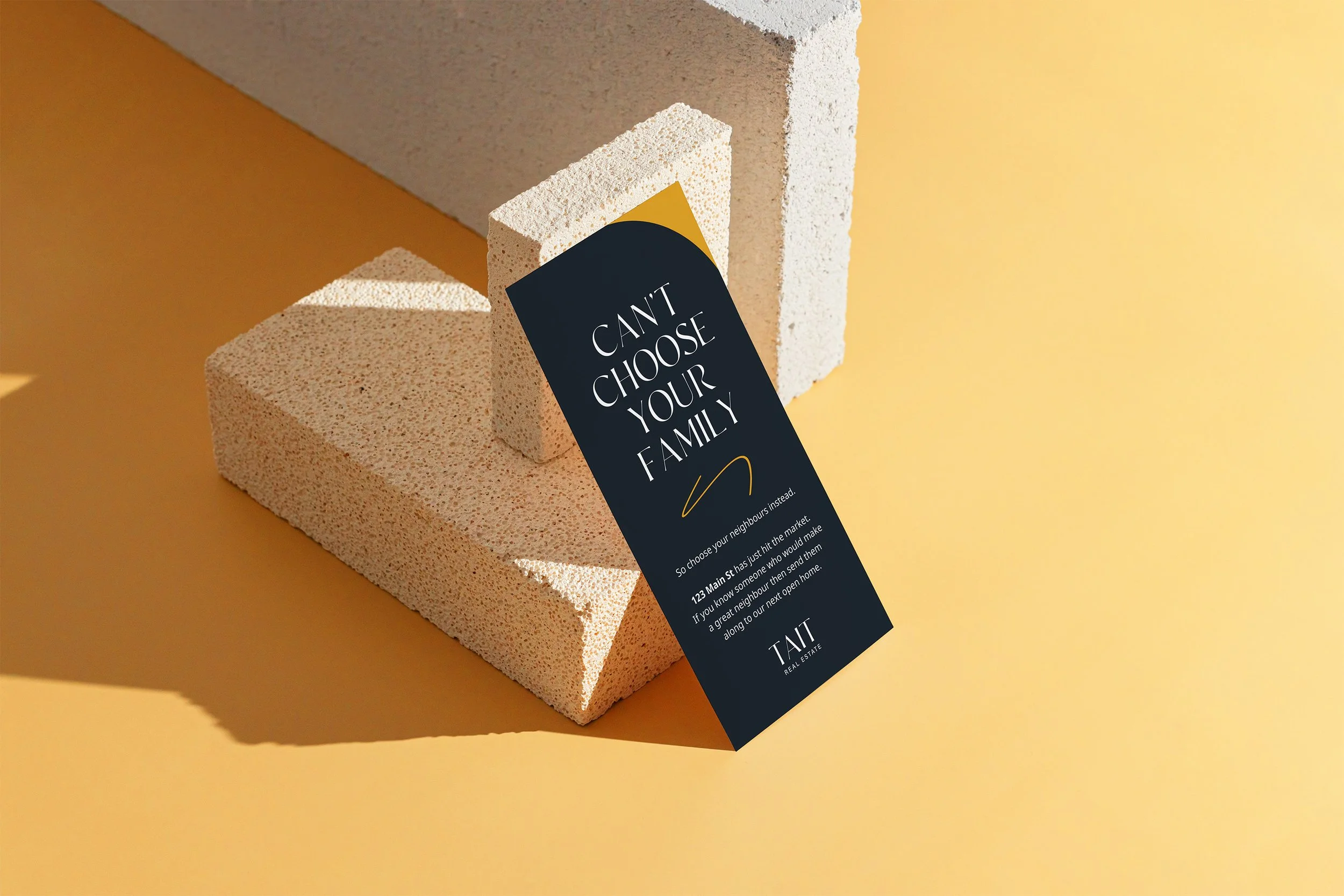 A promotional flyer attached to two white foam blocks against a yellow background. The flyer has text encouraging family choice and includes a URL for a real estate company.