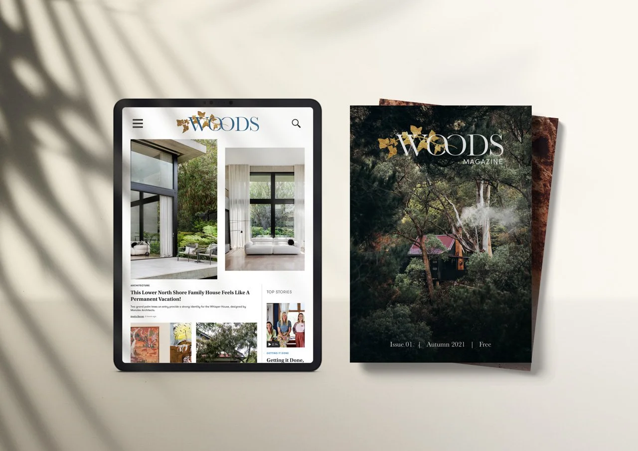 Woods magazine issue 01 Autumn 2021 placed on a desk next to a tablet displaying a website about architecture, with greenery seen through large windows in the images.