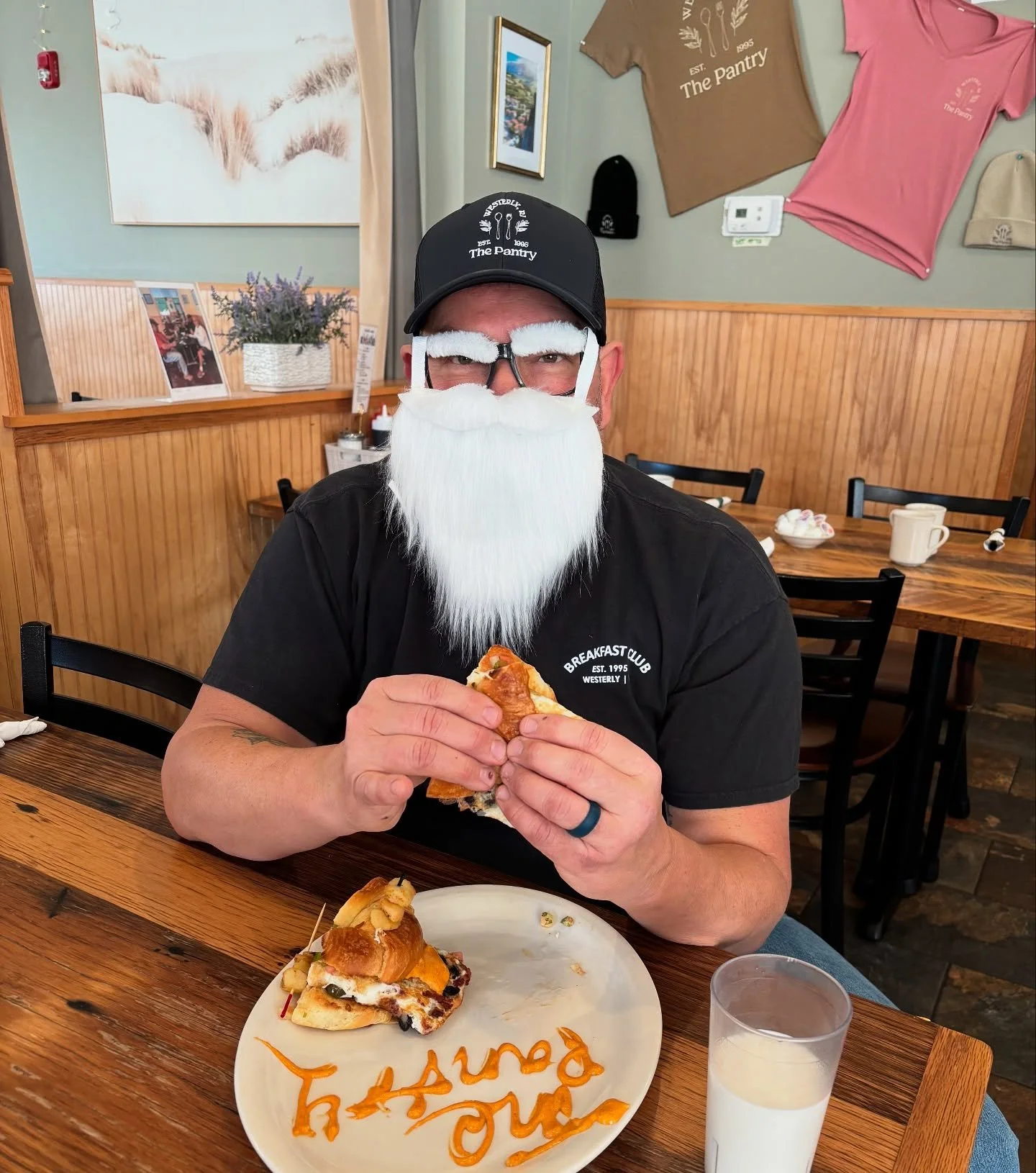 🎅✨ Santa&rsquo;s fueling up for the big day &mdash; and of course he stopped at The Pantry!
Our manager Brian is rocking his Santa beard, Pantry tee, and Pantry hat&hellip; plus the most important accessory: a breakfast sandwich! 😋🥪

Looking for l