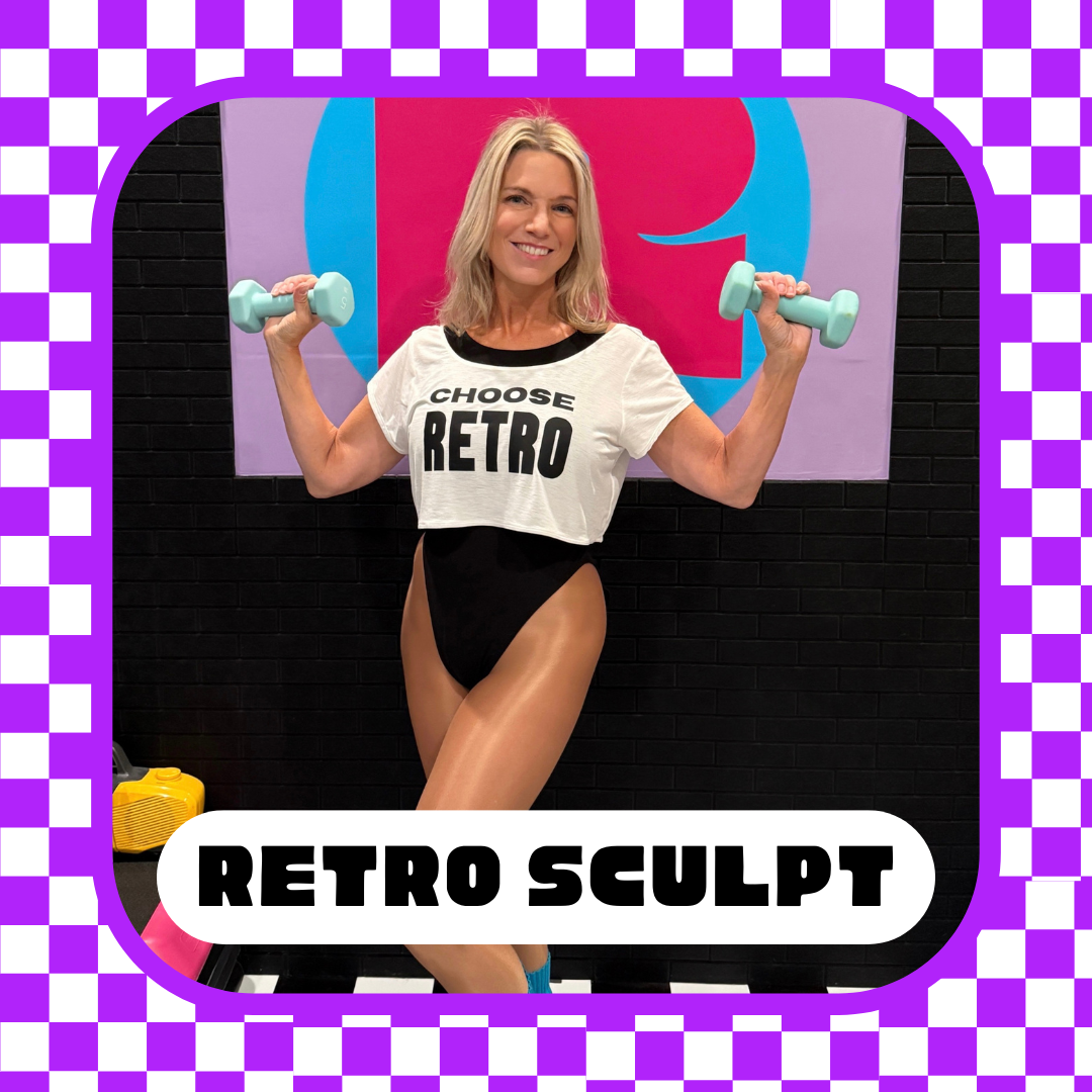 A woman lifting light blue dumbbells in a gym, wearing a white crop top with the words 'Choose Retro' and black high-waisted shorts, standing in front of a colorful background with a black brick wall.