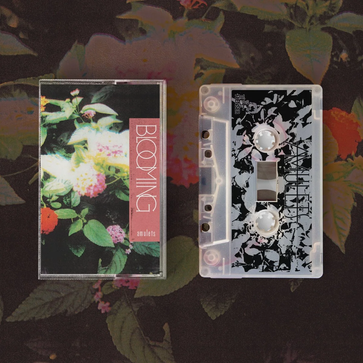 A cassette tape and its cover featuring a floral design, placed on a surface with a dark floral background.