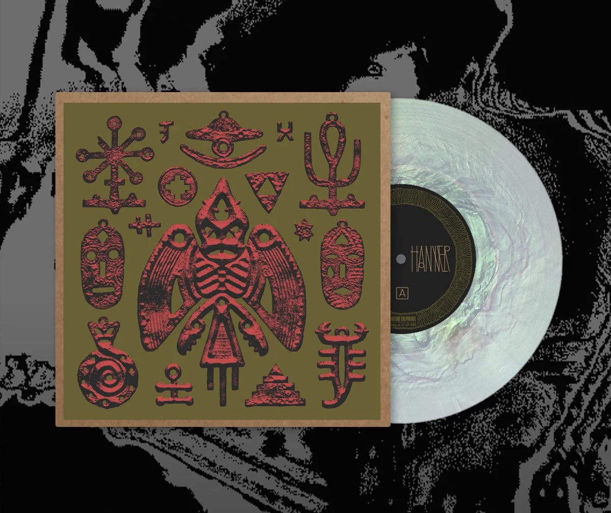 A vinyl record with a cover featuring various tribal or mystical symbols in red on an olive-green background, placed behind the record. The record label shows the name 'JENNY HANIVER' and side 'A'.