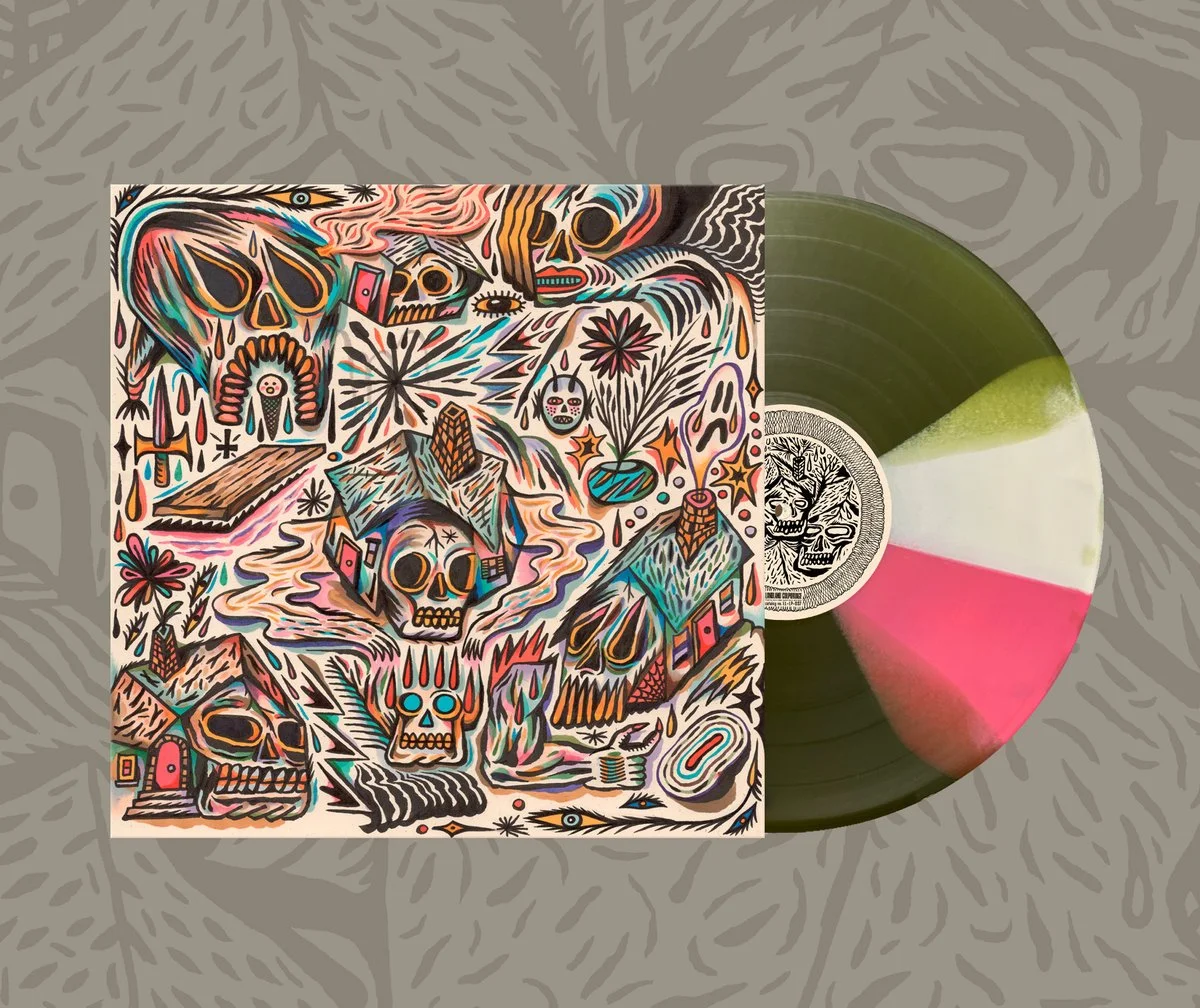 A vinyl record with a tri-color (black, white, green, pink) swirl pattern, featuring a label with a skull illustration. The album cover displays a colorful, abstract artwork with skulls, houses, and various shapes in neon and pastel colors.
