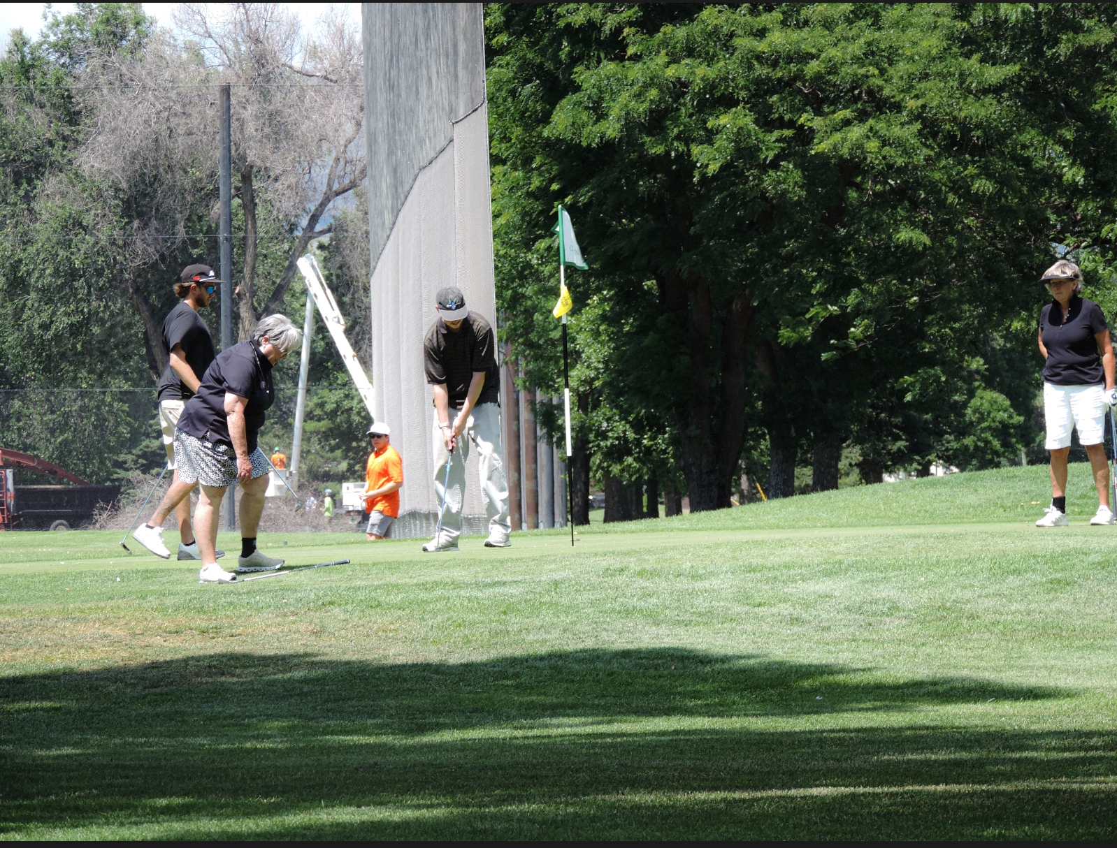 Opponents lining up a "feel good" putt after the winning putt is made, on the 9th green of the city park golf course on July 11th 2025 at 12:15 pm for a photgraphy essay