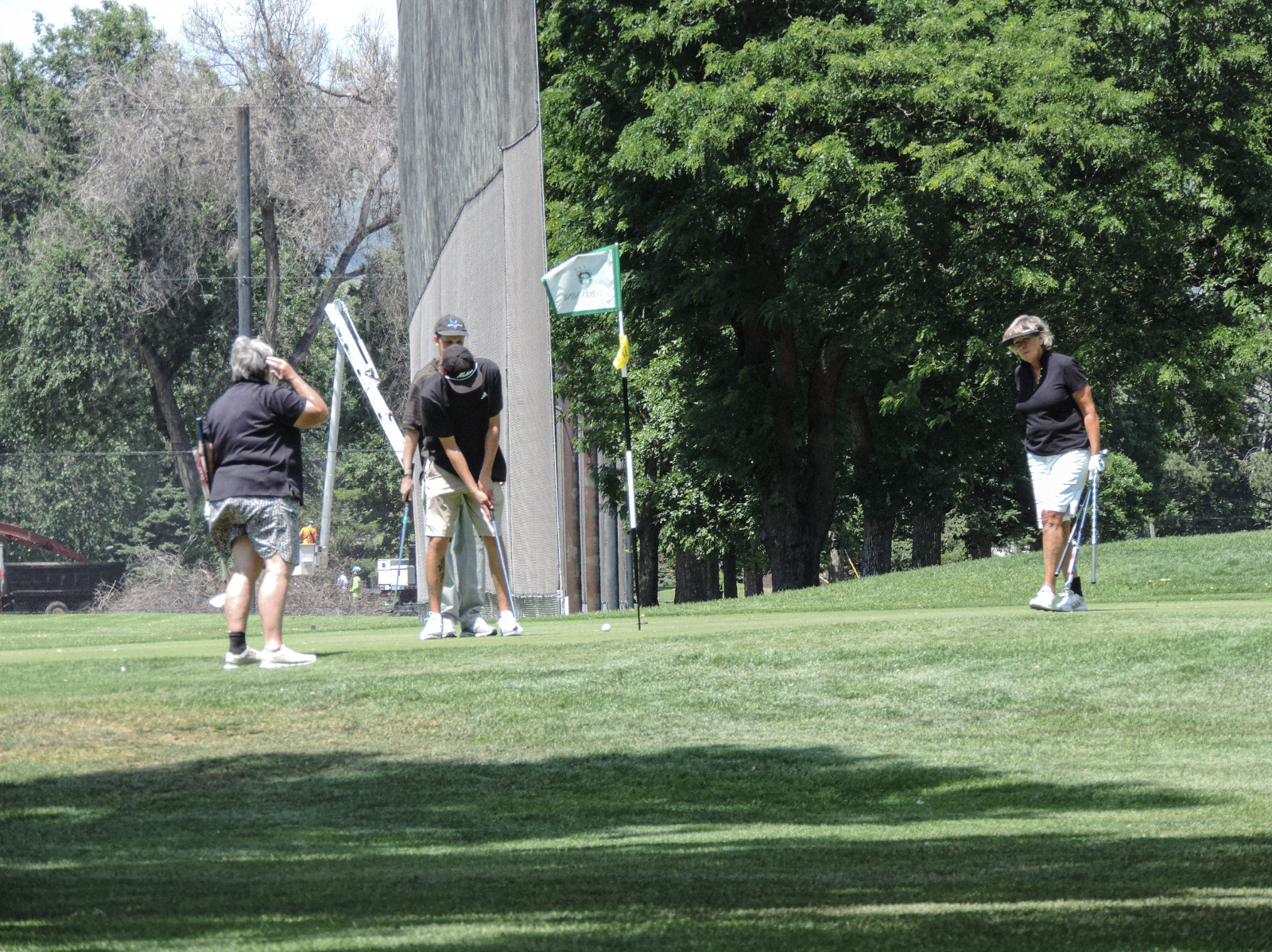 Opponents make the "feel good" putt after the winning putt is made, on the 9th green of the city park golf course on July 11th 2025 at 12:15 pm for a photgraphy essay