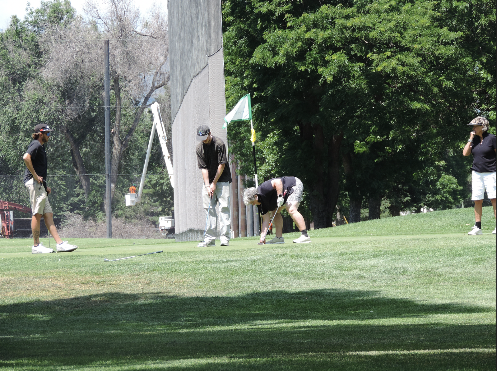 Following their match winning putt, she picks up her ball out of the cup, on the 9th green on of the city park golf course on July 11th at 12:15pm for a photgraphy essay