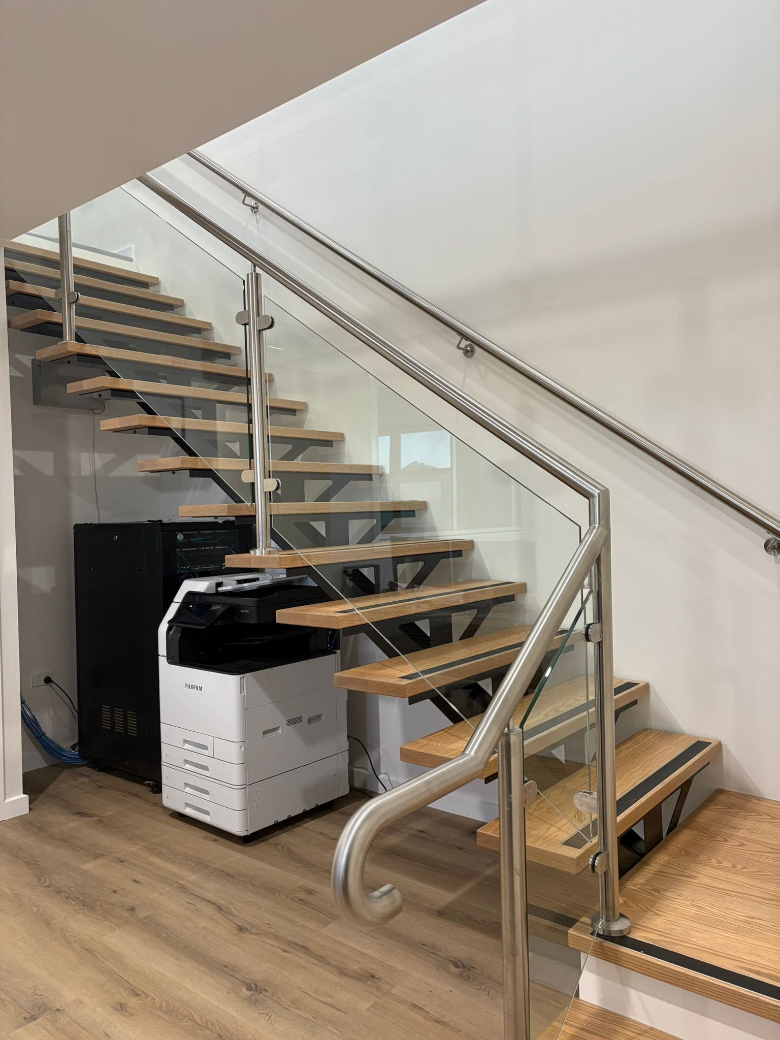 Floating timber and steel staircase with a stainless steel and glass balustrade in the Nolan St commercial fit-out by AMW Builders in Bendigo.