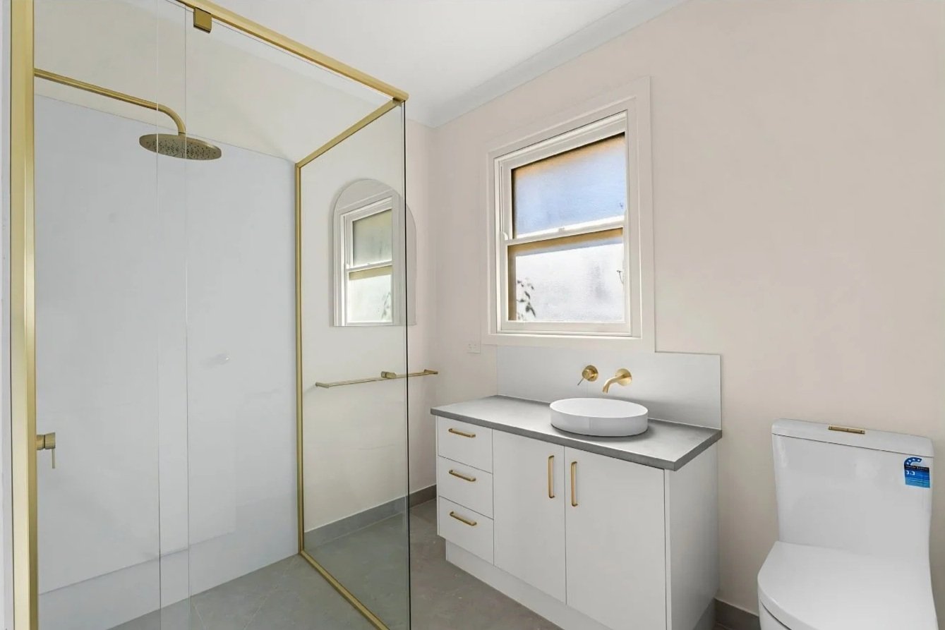 Renovated bathroom with a glass walk-in shower, brass fixtures and a stone-topped vanity with vessel basin at the Hargreaves St renovation in Bendigo.