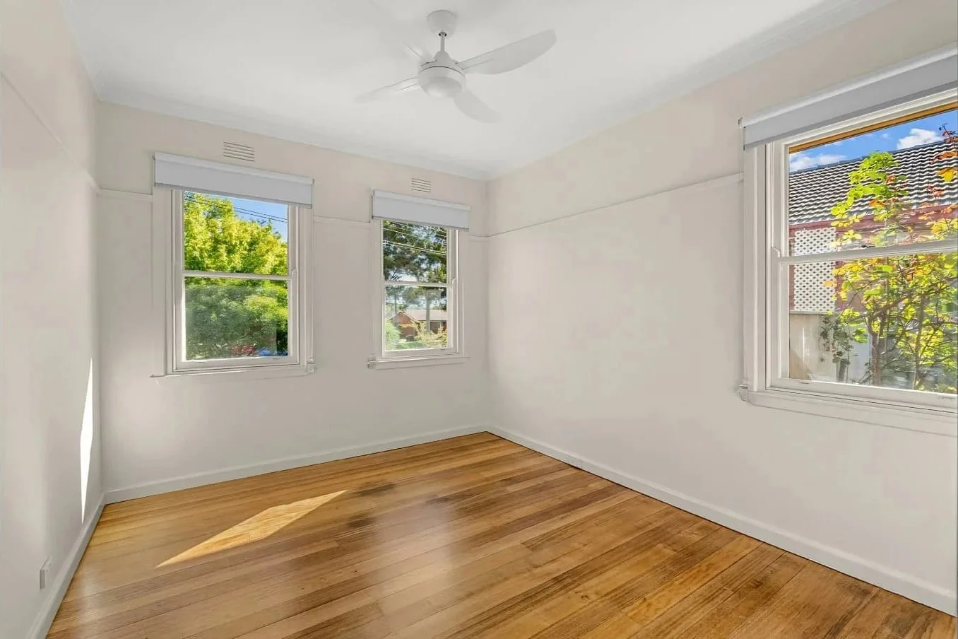 Freshly renovated bedroom with polished timber floors, white walls and garden-facing windows at the Hargreaves St renovation in Bendigo.
