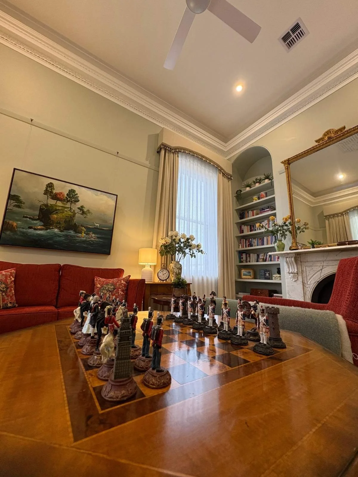 Heritage lounge with high ornate ceilings, a marble fireplace, built-in bookshelves and an inlaid games table at the Barkly St project in Bendigo.